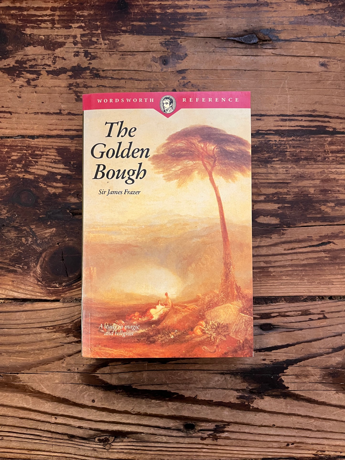 Front cover of book titled 'The Golden Bough' by James G. Frazer on a wooden surface
