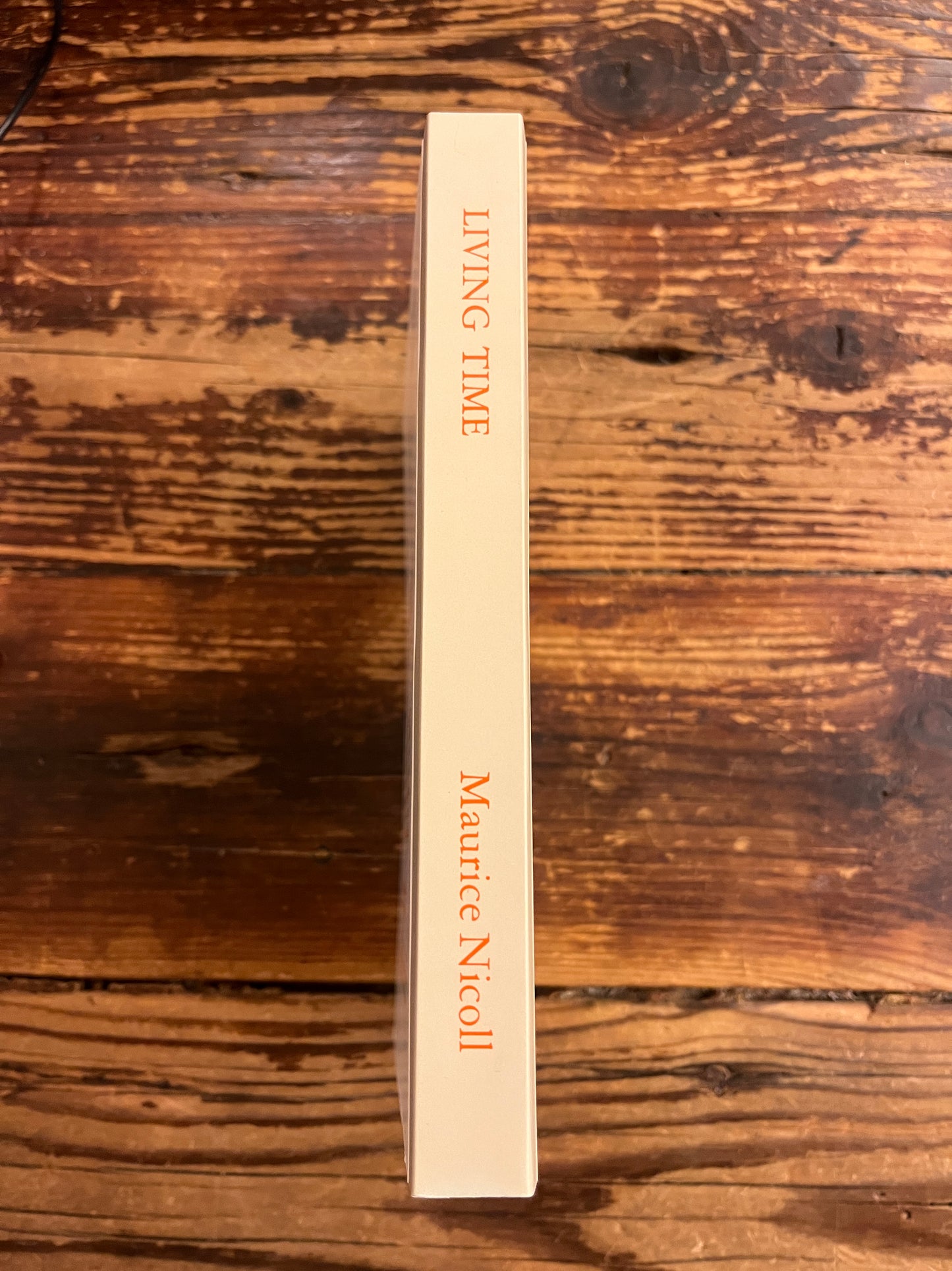 Spine of book titled 'living time' by Maurice Nicoll on wooden surface