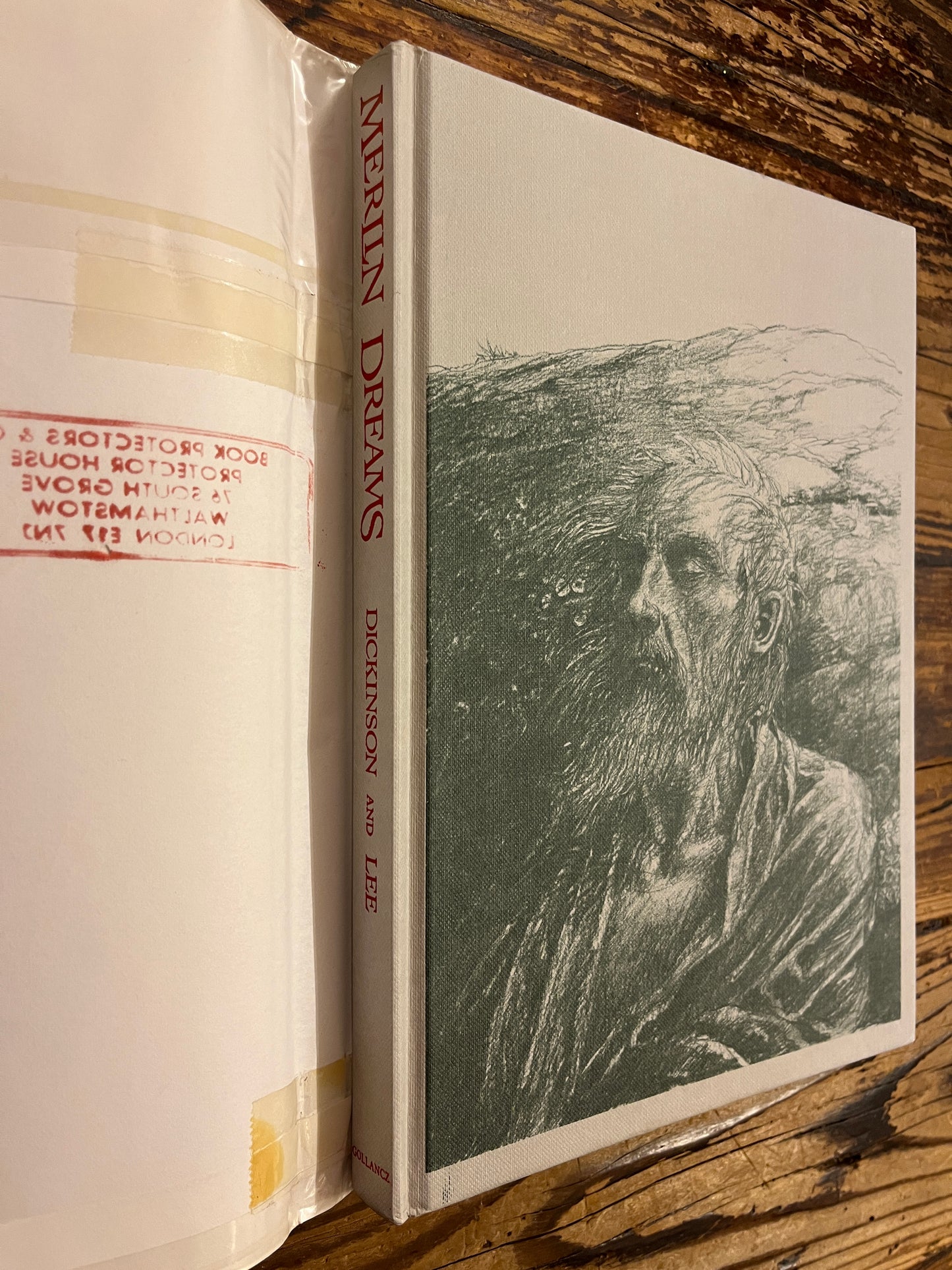 front cover and spine without dust jacket of book titled 'Merlin Dreams' by Peter Dickinson and illustrated by Alan Lee on a wooden surface 