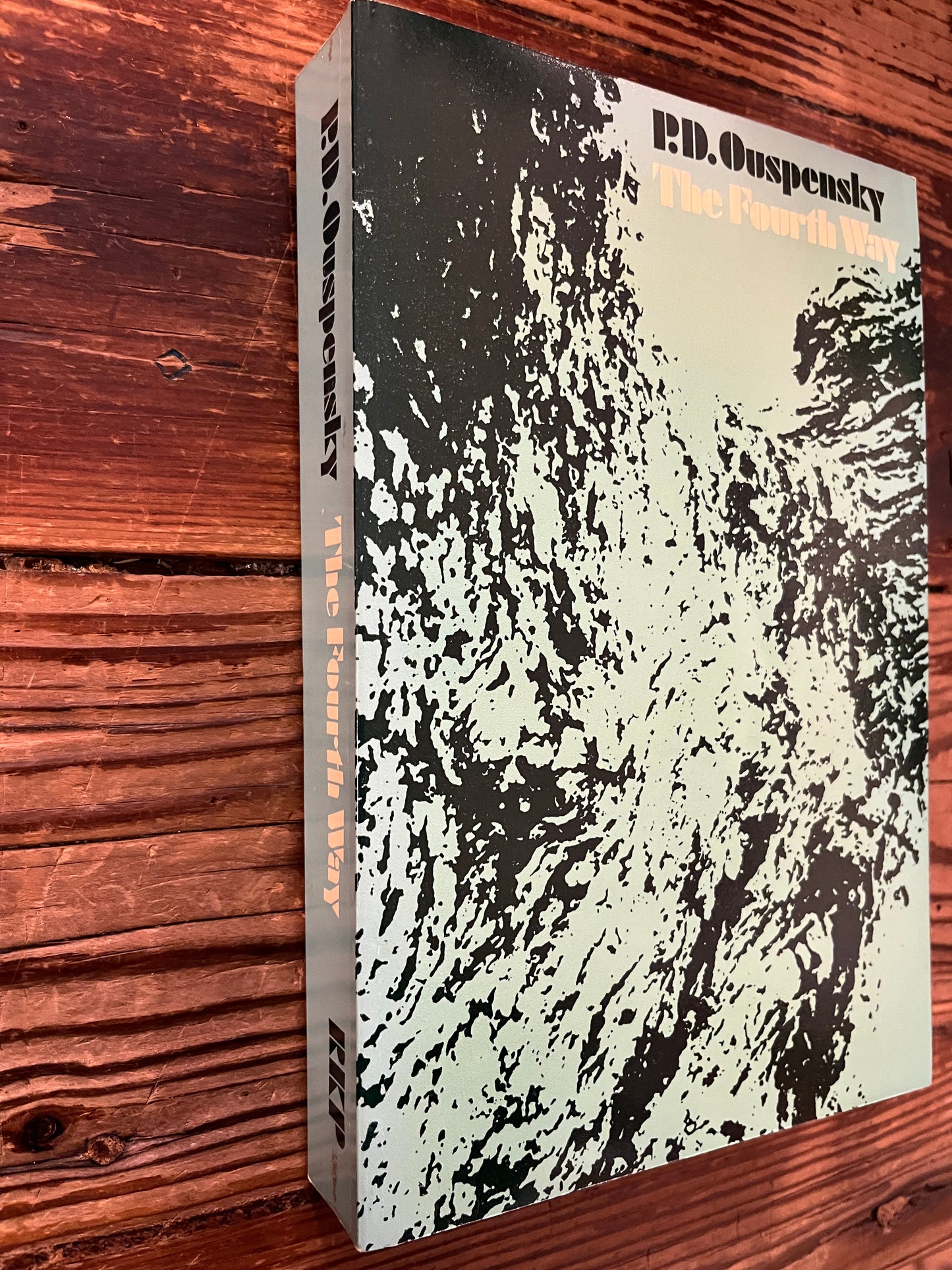 Cover of a book with the title 'the fourth way' by P.D. Ouspensky on a wooden surface 