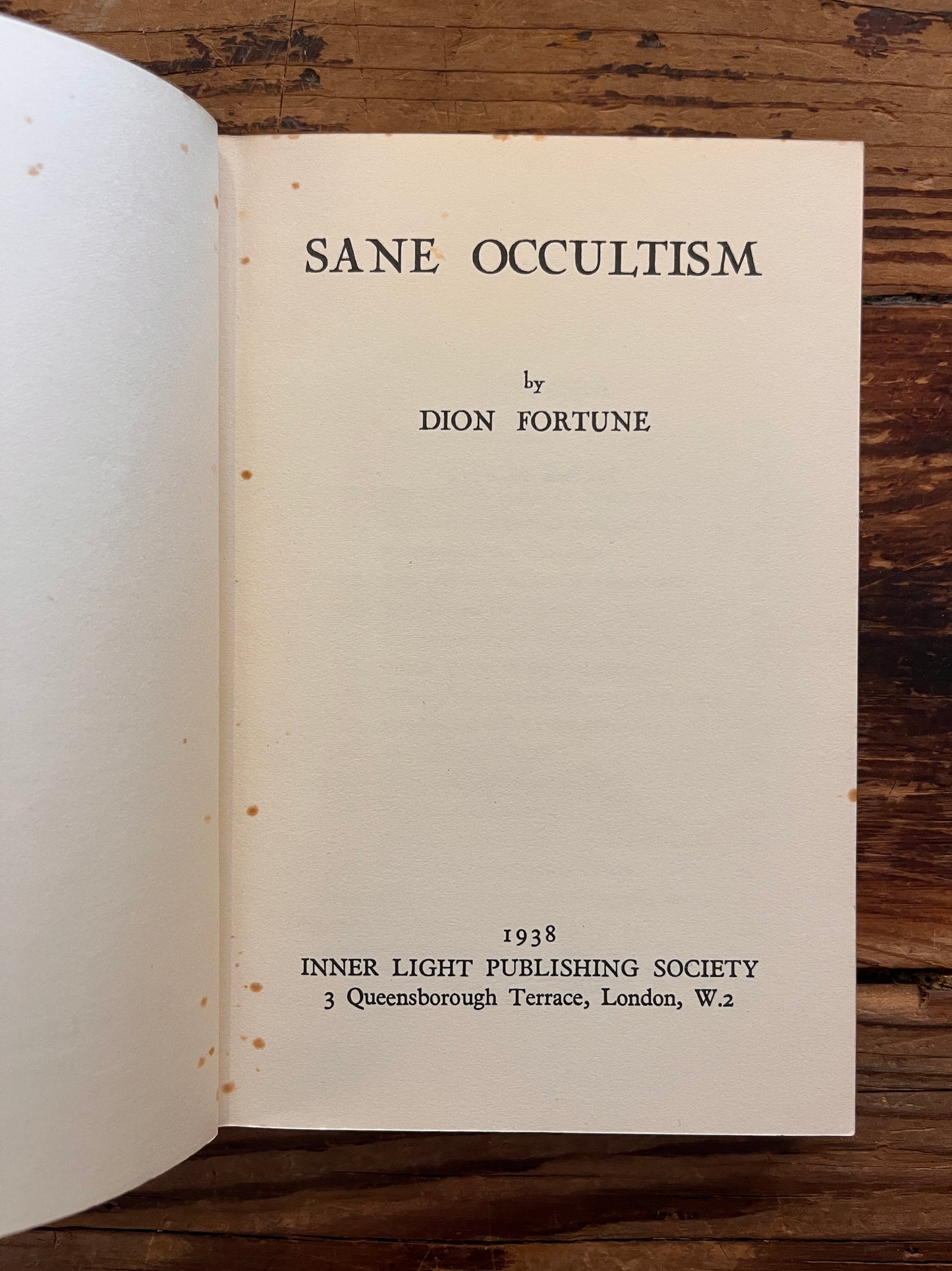 Title page of rare first cheap edition of book titled 'sane occultism' by Dion Fortune on a wooden surface 