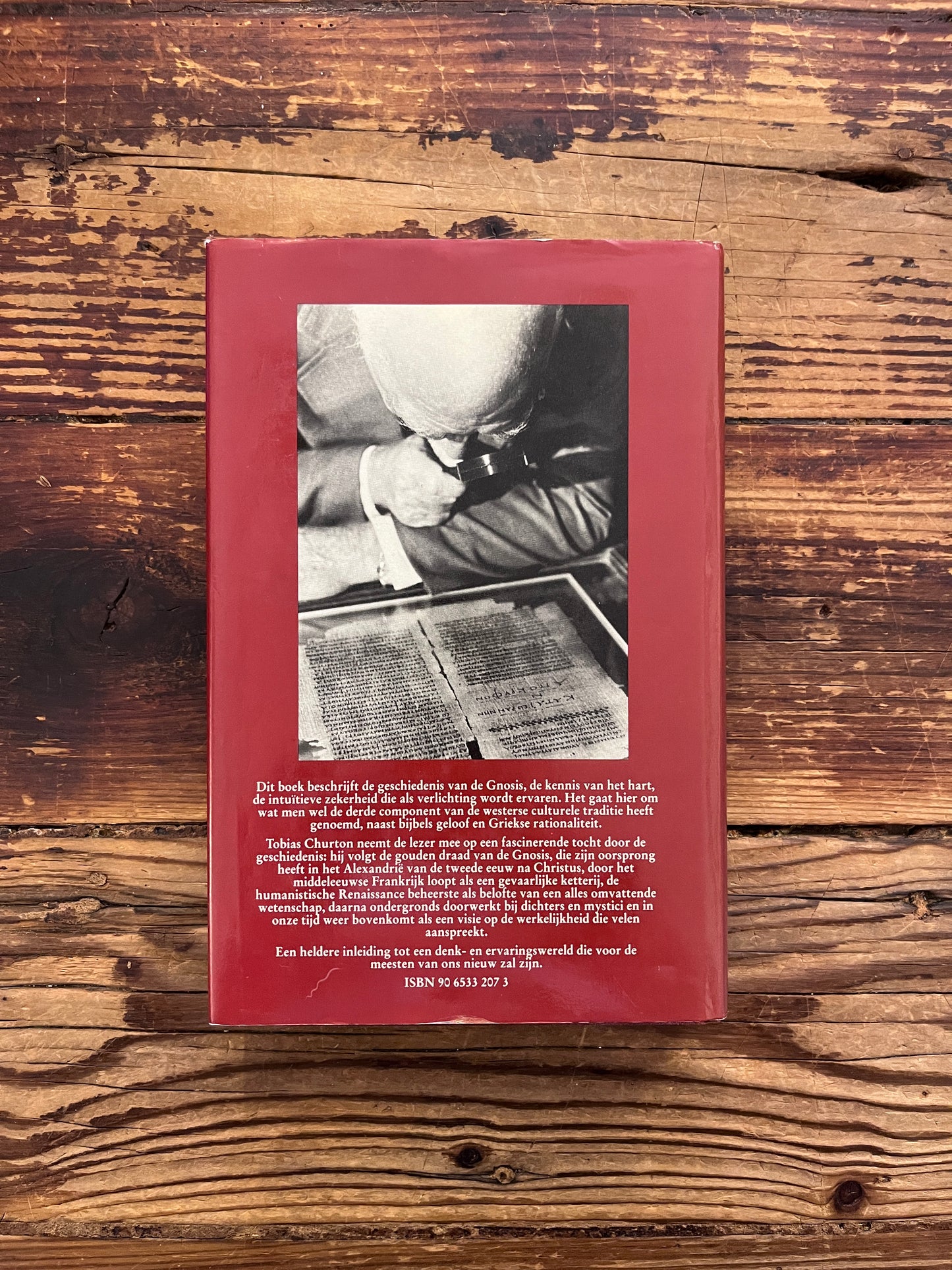 Achterkant van boek met de titel 'geschiedenis van de gnosis' door Tobias Churton op een houten achtergrond 