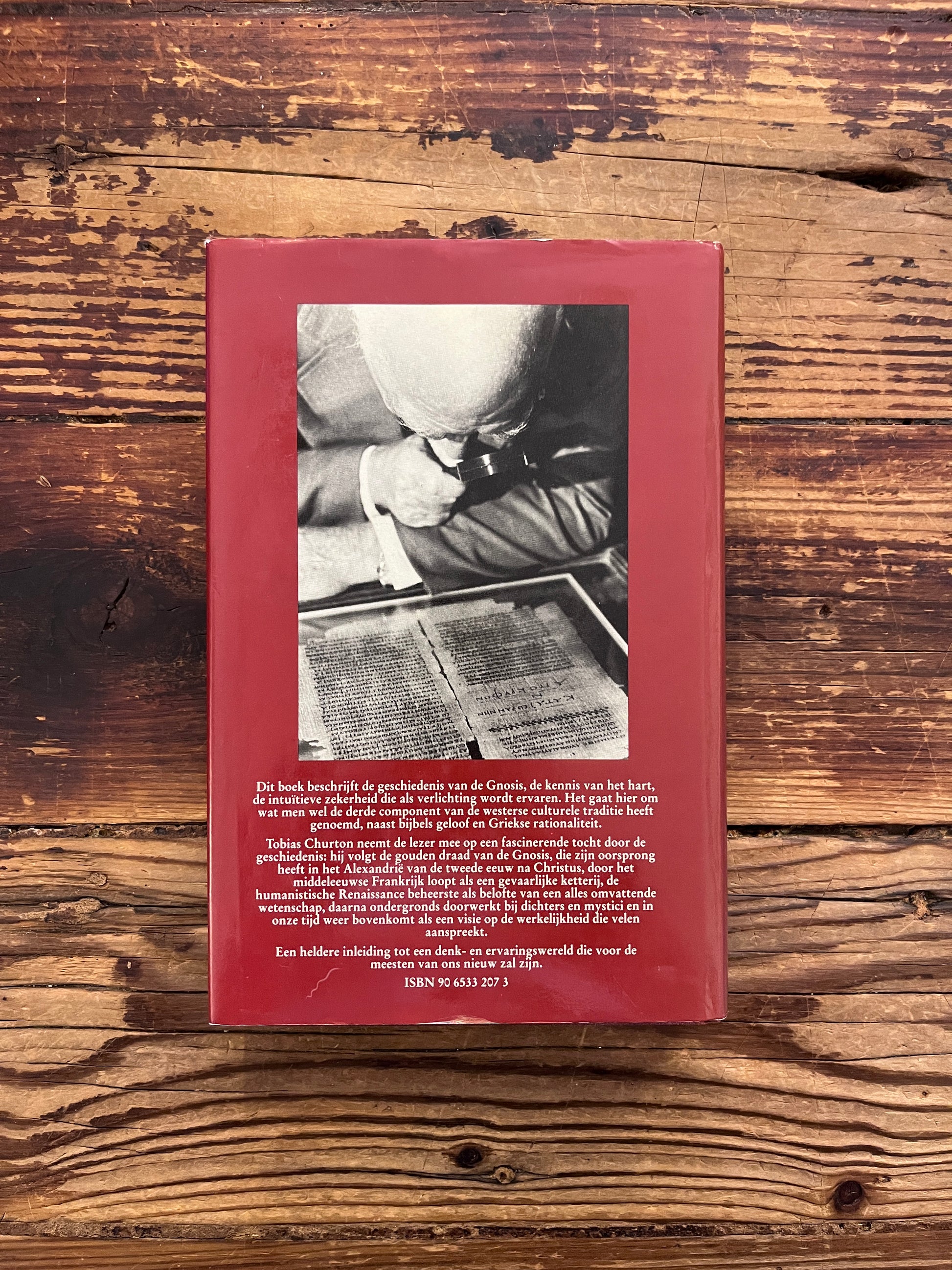 Achterkant van boek met de titel 'geschiedenis van de gnosis' door Tobias Churton op een houten achtergrond 