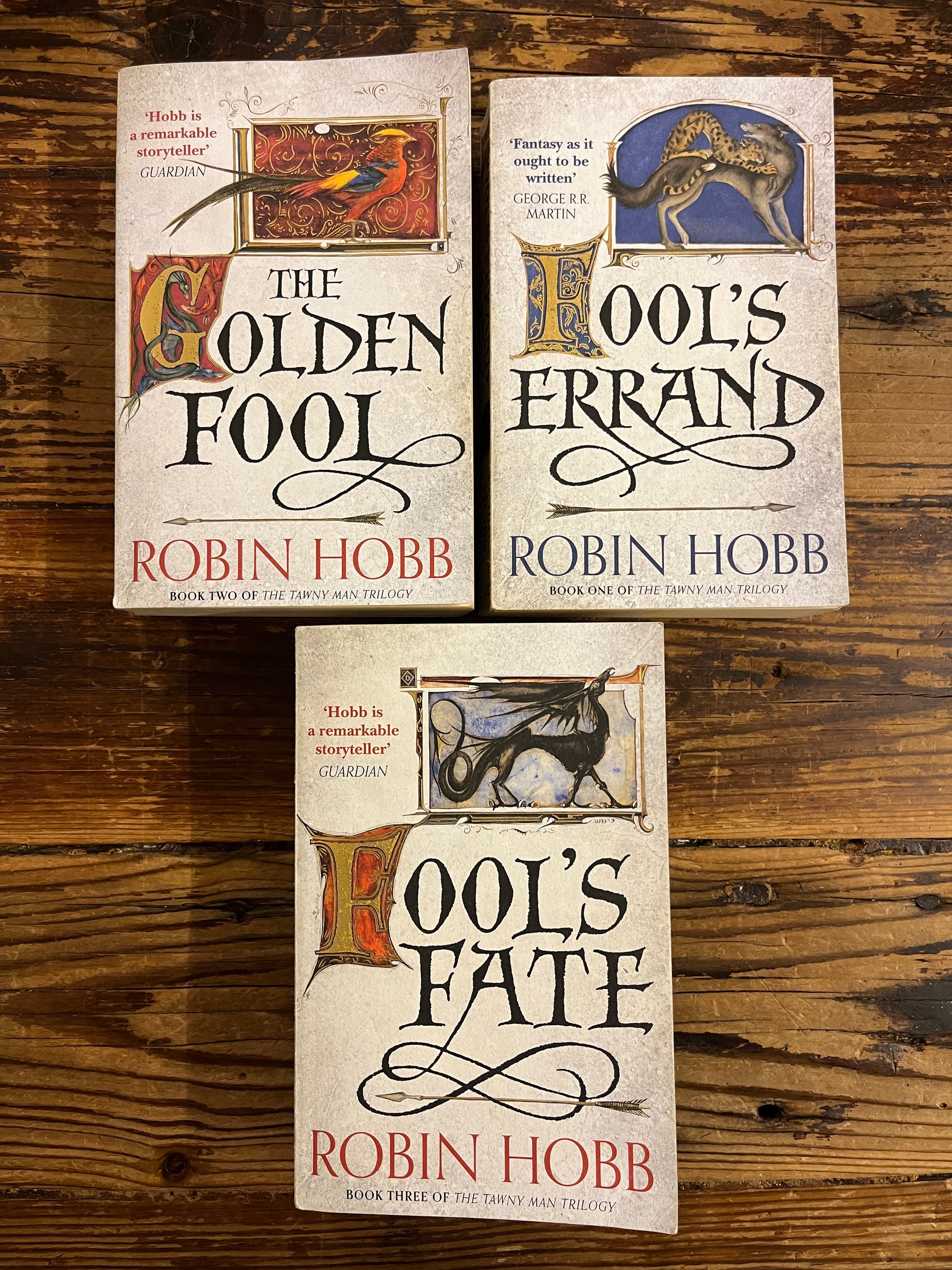 the three books of Robin Hobb's 'Tawny Man's trilogy' on a wooden surface