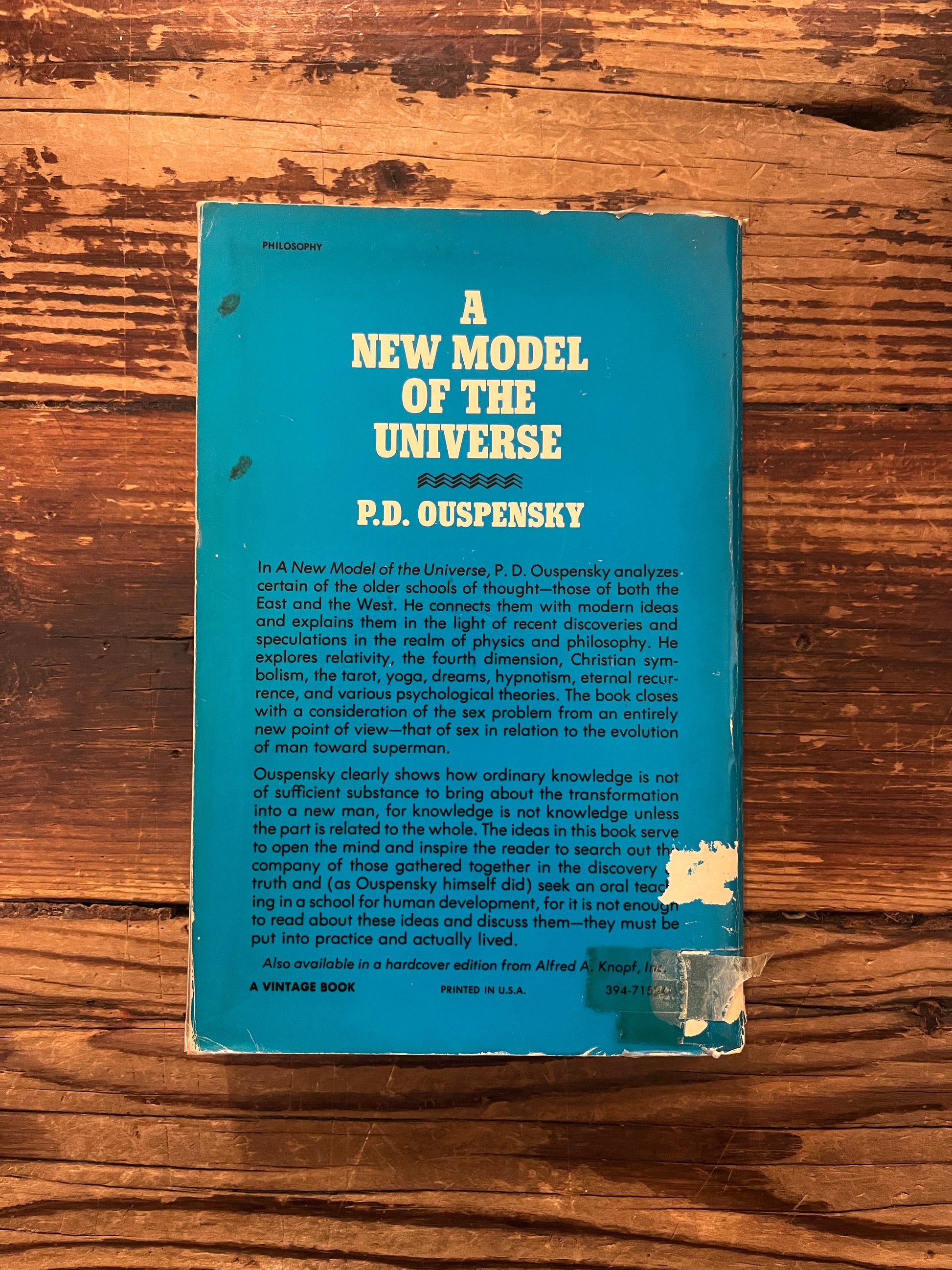 back cover of book titled 'A New Model of the Universe' by P.D. Ouspensky on a wooden surface