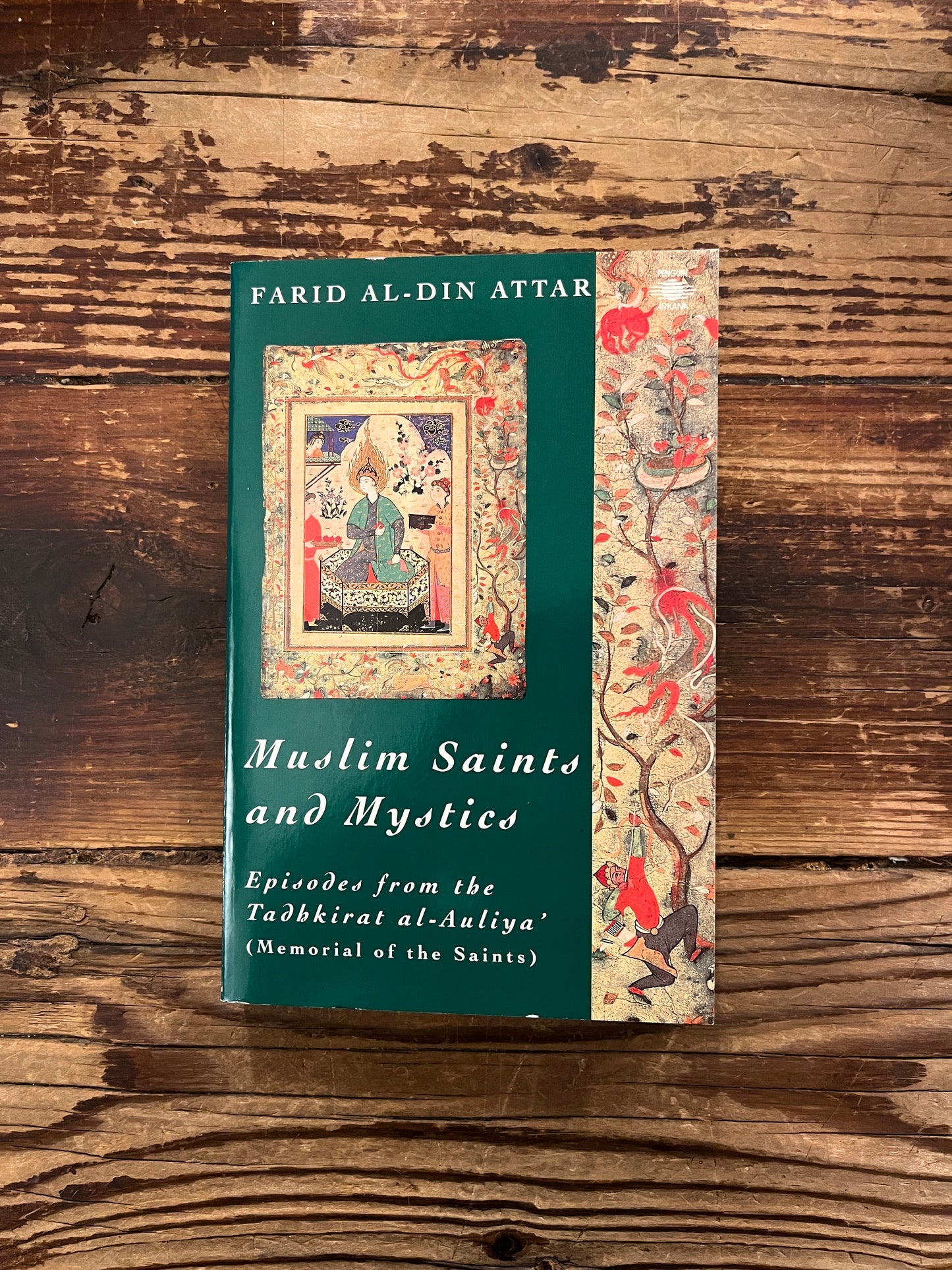 Book titled 'Muslim Saints and Mystics' by Farid al-Din Attar on a wooden surface