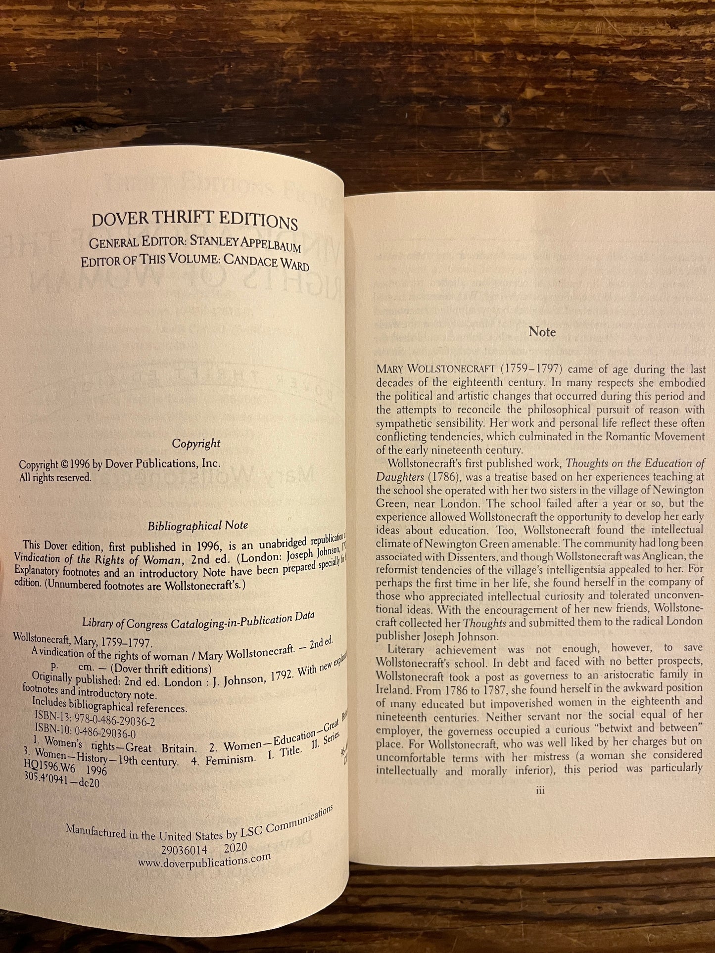 Open book titled 'A Vindication of the Rights of Woman' by Mary Wollstonecraft on a wooden surface