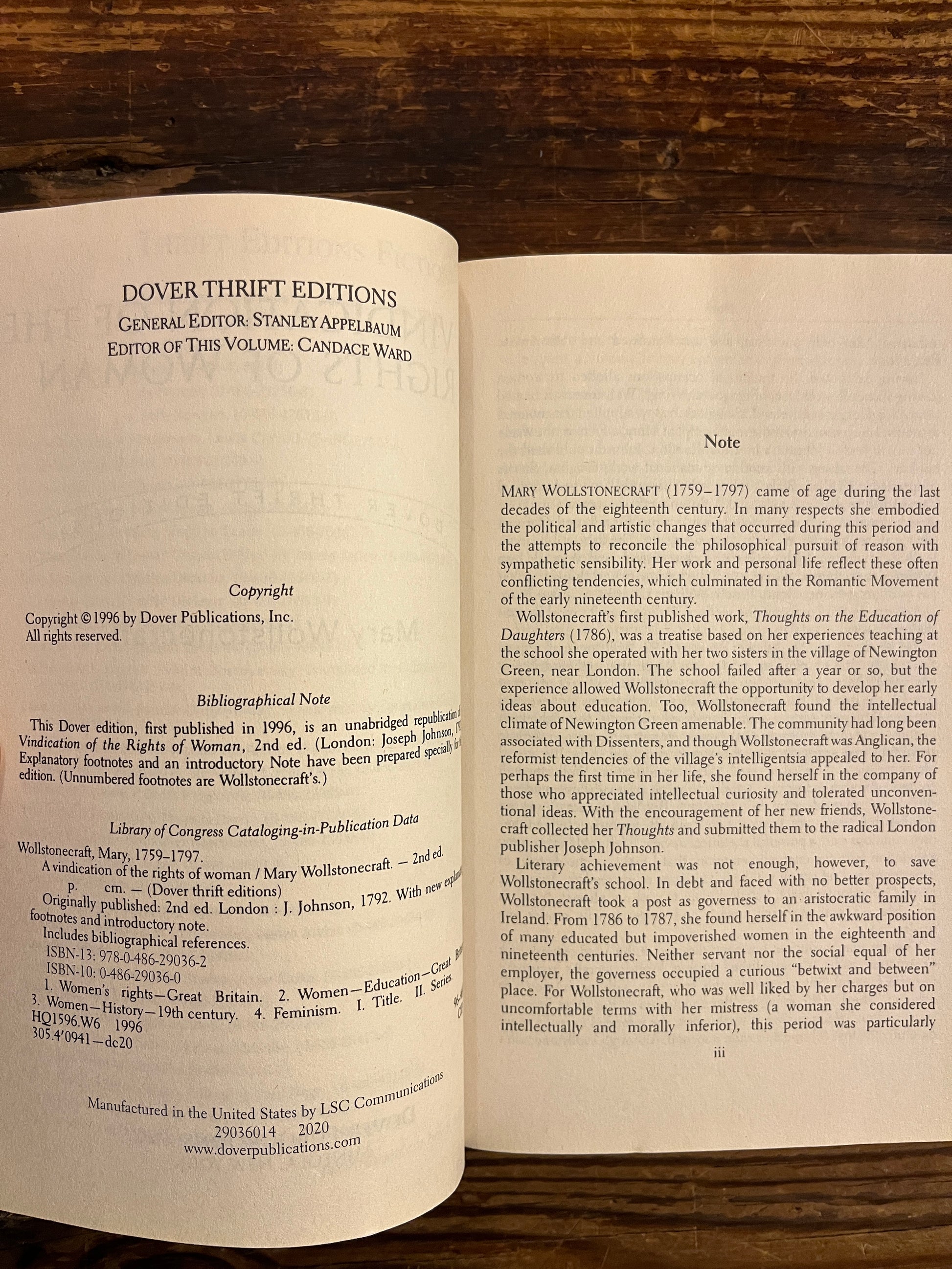 Open book titled 'A Vindication of the Rights of Woman' by Mary Wollstonecraft on a wooden surface