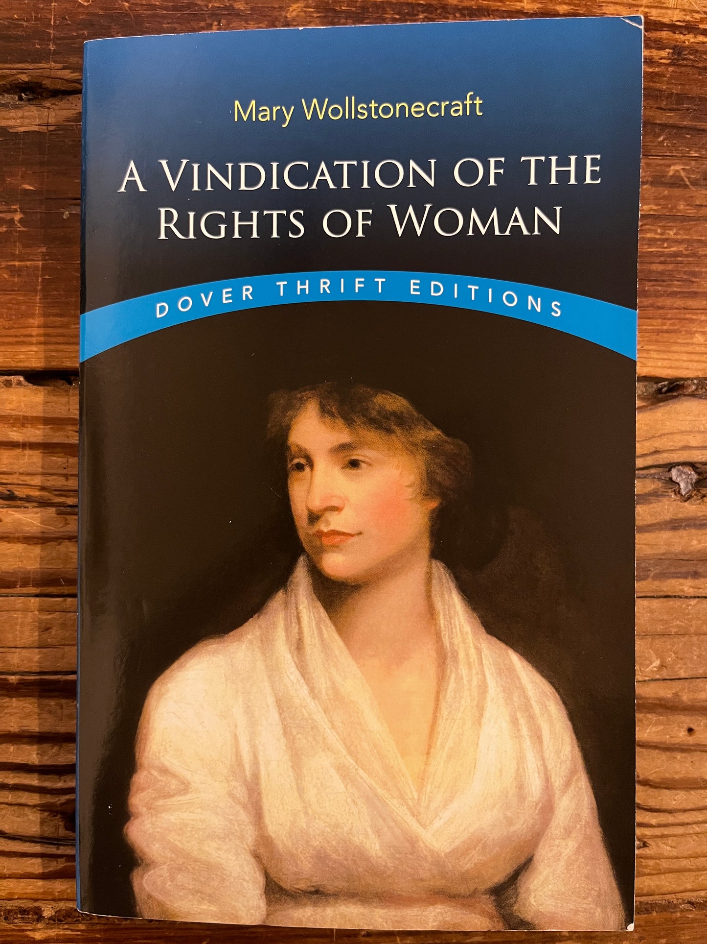 Front cover of book titled 'A Vindication of the Rights of Woman' by Mary Wollstonecraft on a wooden surface