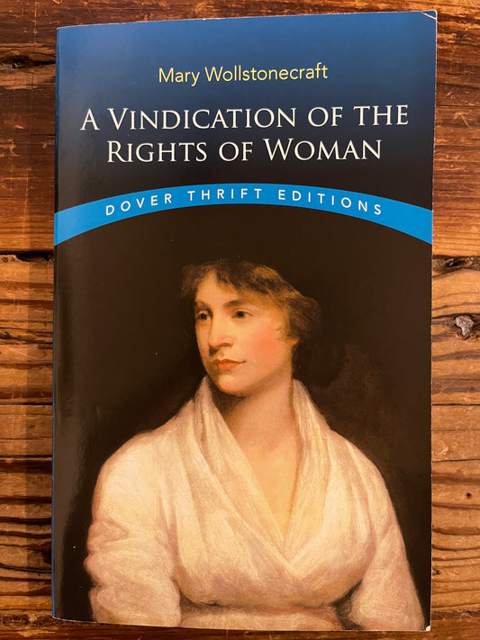Front cover of book titled 'A Vindication of the Rights of Woman' by Mary Wollstonecraft on a wooden surface