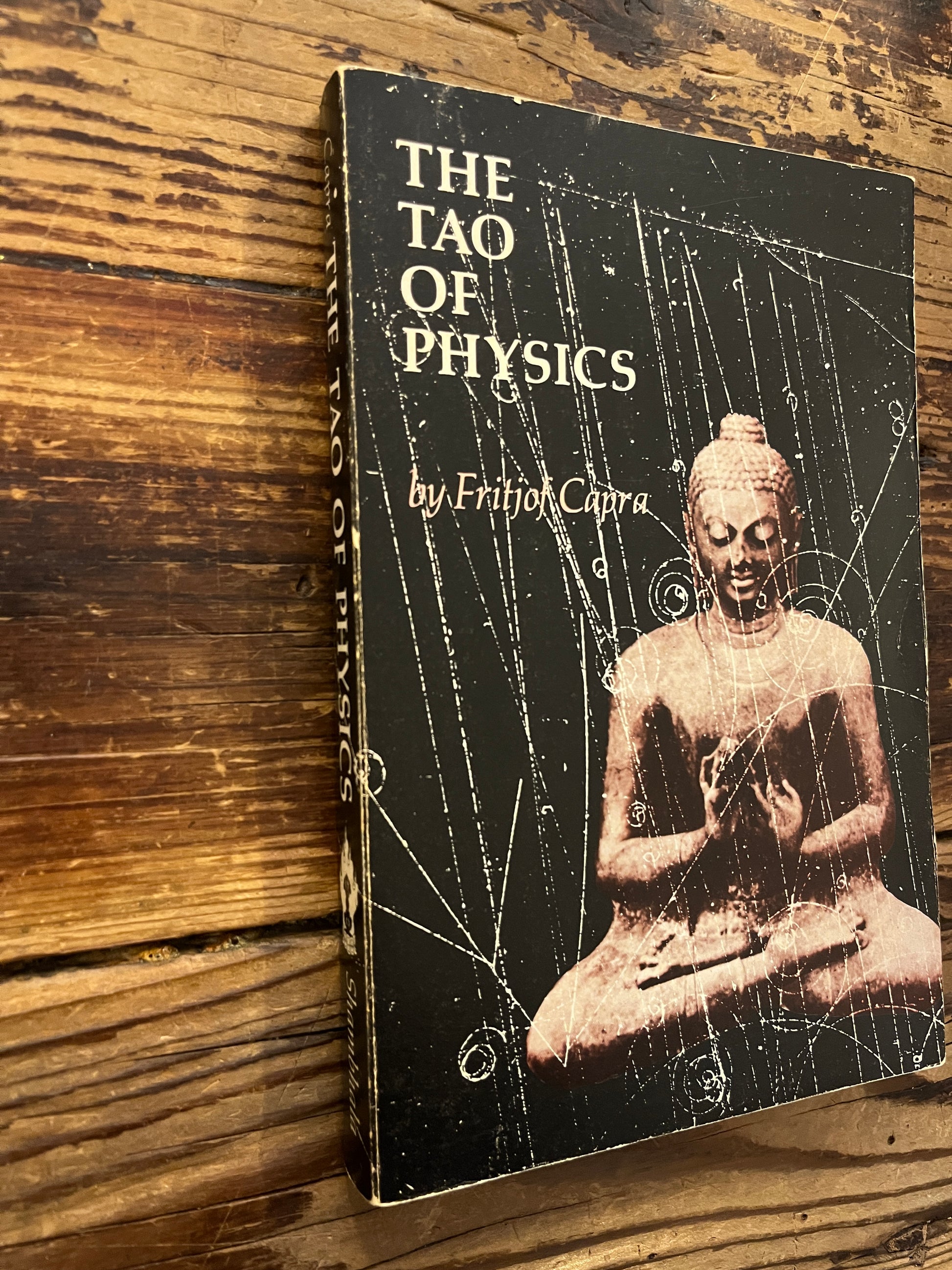 Spine and cover of book titled 'The Tao of Physics' by Fritjof Capra on a wooden surface