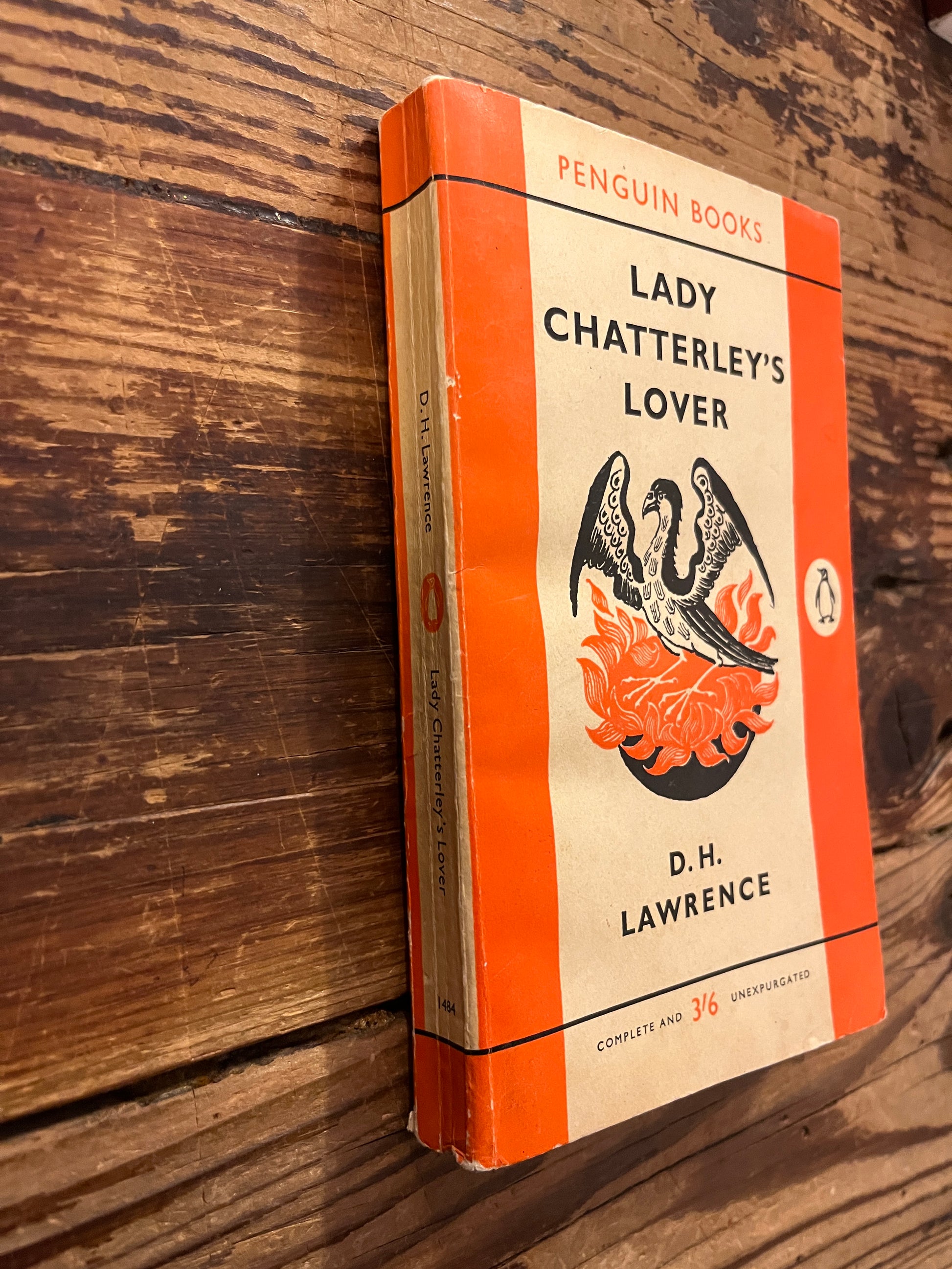 Front cover and spine  of book titled 'Lady Chatterley's Lover' by D.H. Lawrence on a wooden surface