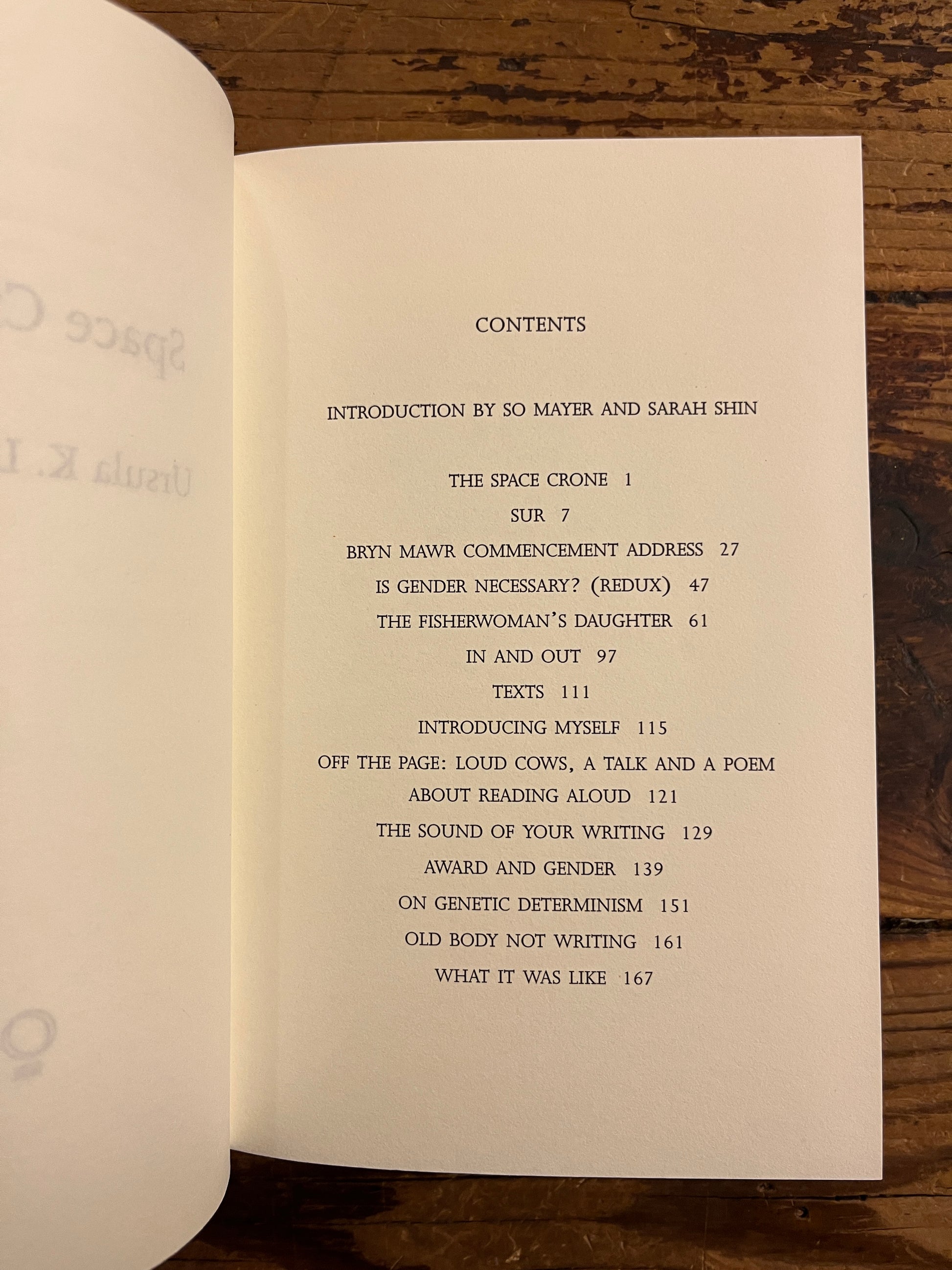 Open book showing the contents of book titled 'Space Crone' by Ursula K. Le Guin on a wooden surface