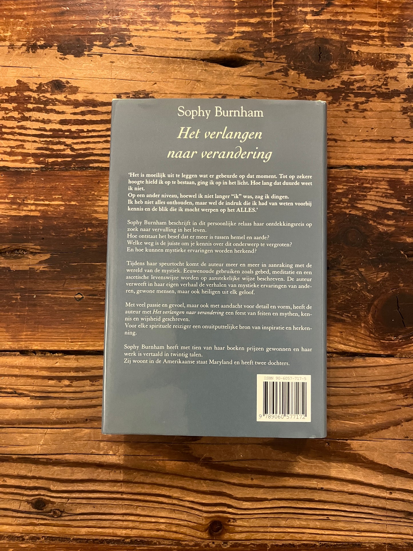 Achterkant van boek met de titel 'het verlangen naar verandering' door Sophy Burnham op een houten achtergrond 