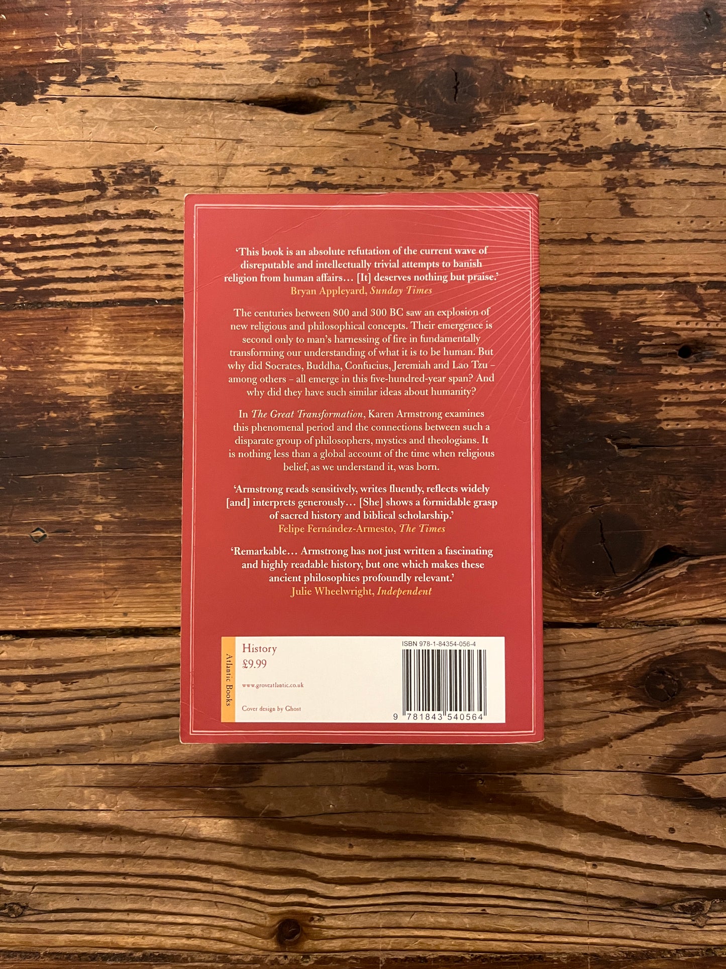 Backcover of the book with the title 'The great transformation' by Karen Armstrong on a wooden surface
