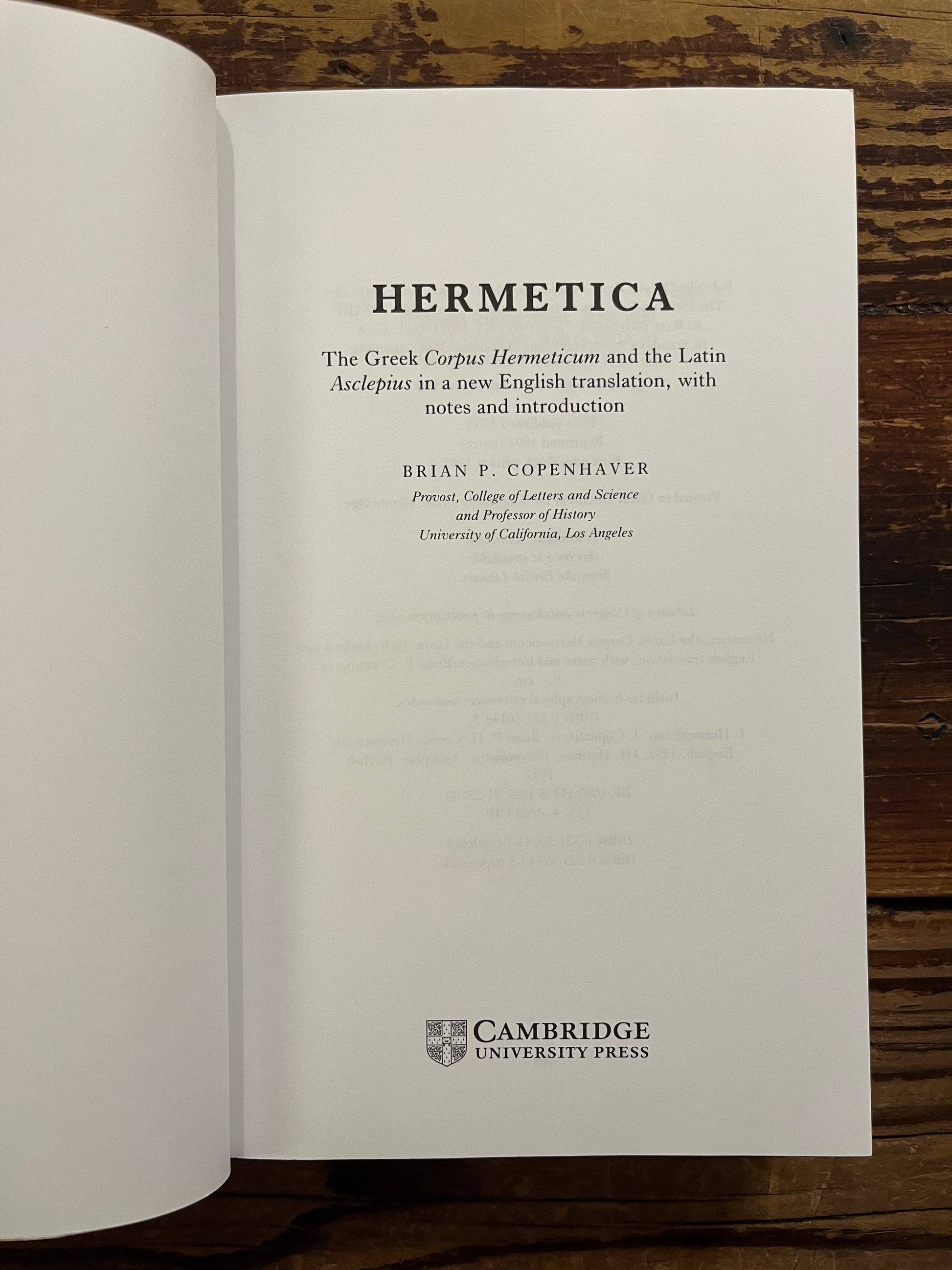 Open book with the title 'Hermetica' door Brian P. Copenhaver on a wooden surface
