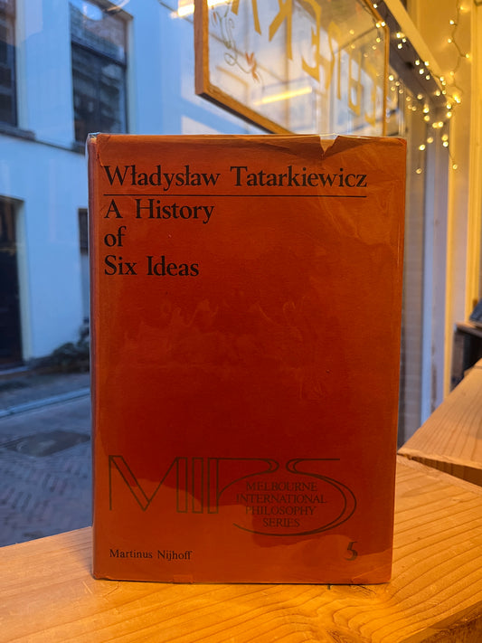 Book titled 'A History of Six Ideas' by Wladyslaw Tatarkiewicz exposed on a wooden shelf.