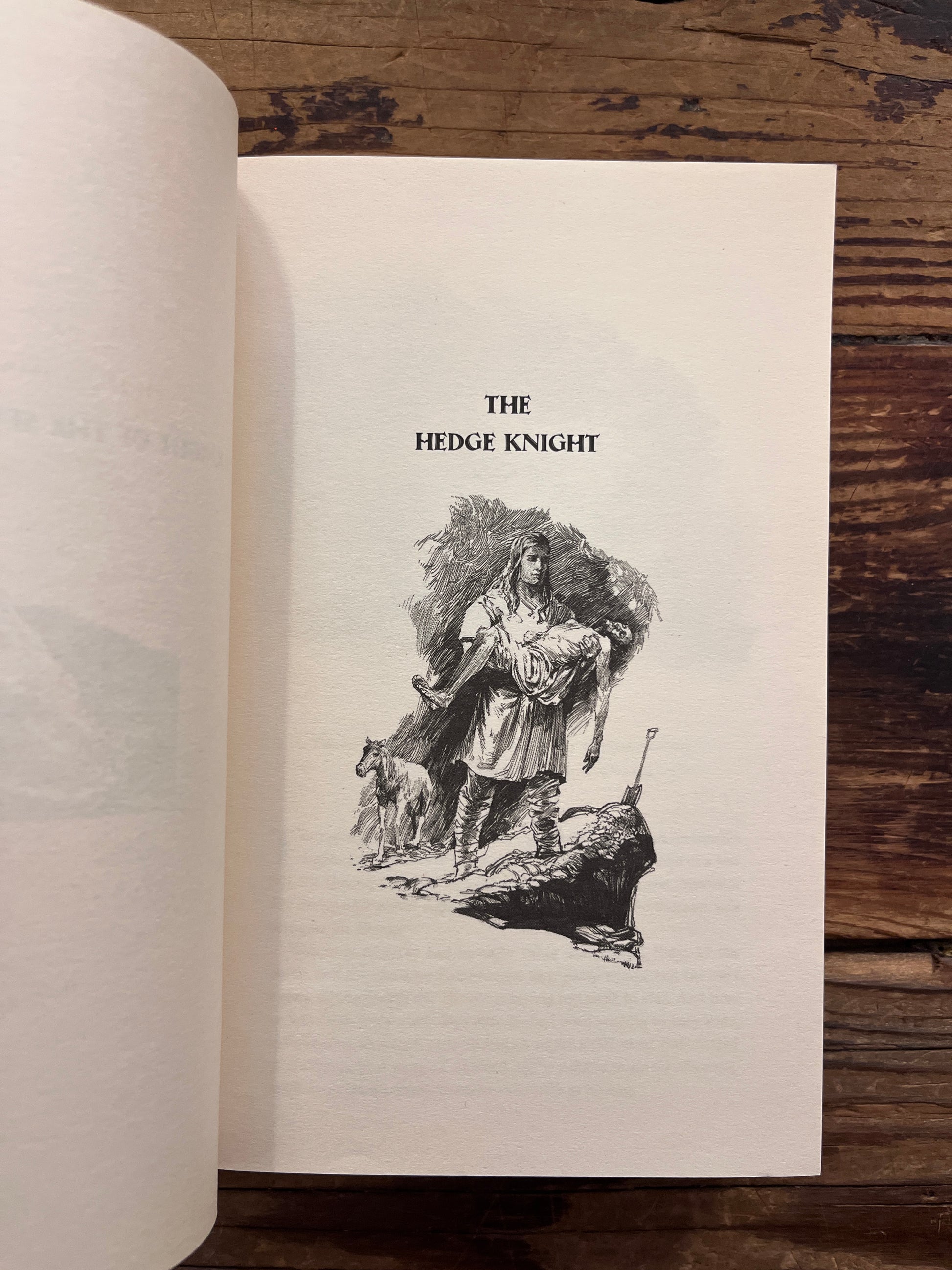 First page of book titled 'A Knight of the Seven Kingdoms' by George R.R. Martin on a wooden surface