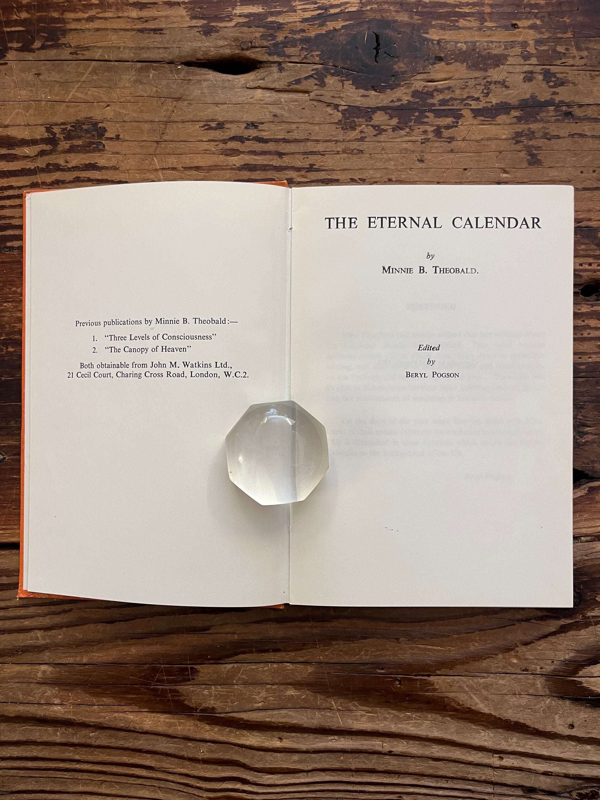 Open book with the tile 'the eternal calendar' by Minnie Theobald on a wooden surface