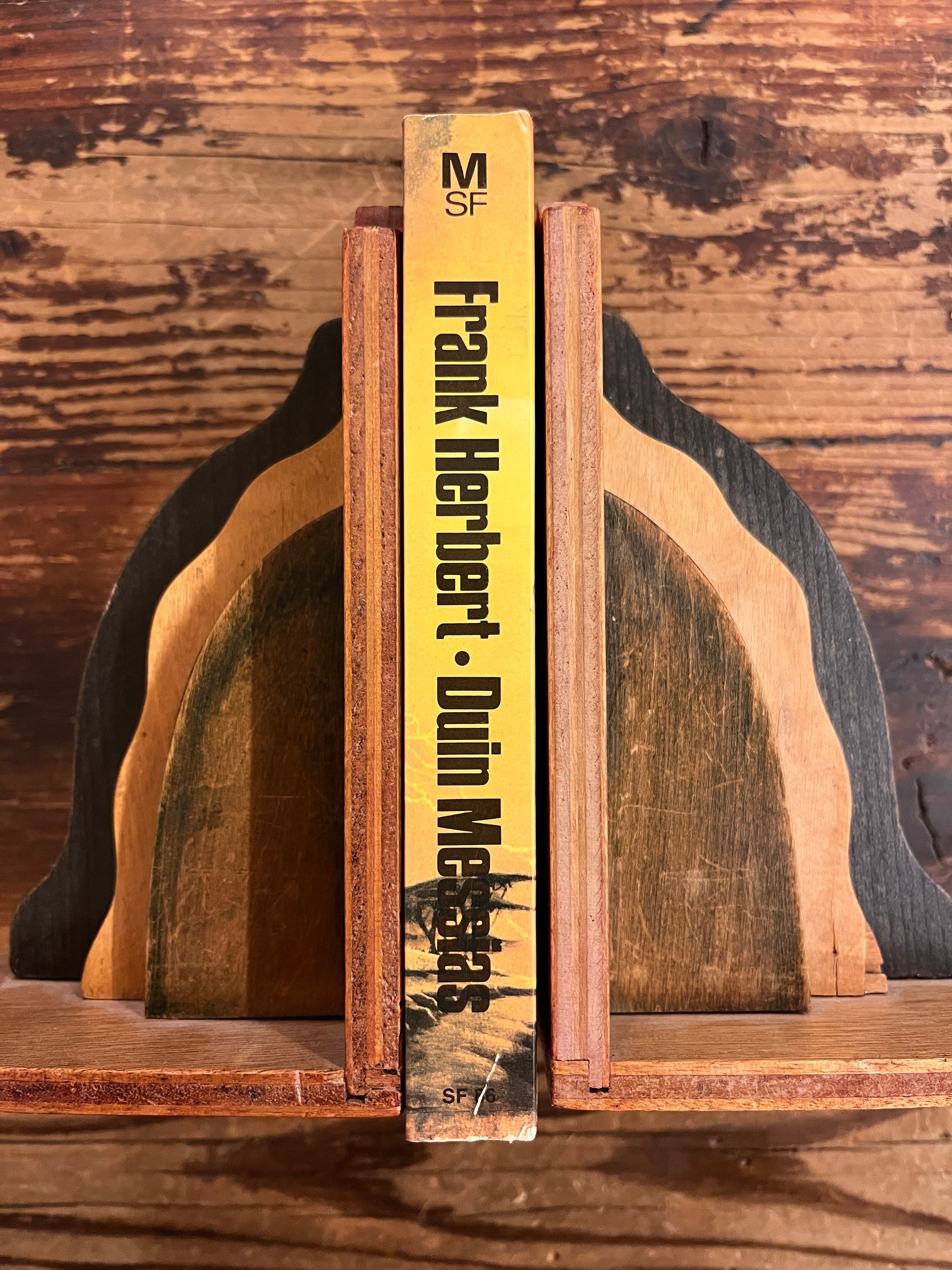 Rug van boek met de titel 'Duin Messias' door Frank Herbert op een houten achtergrond