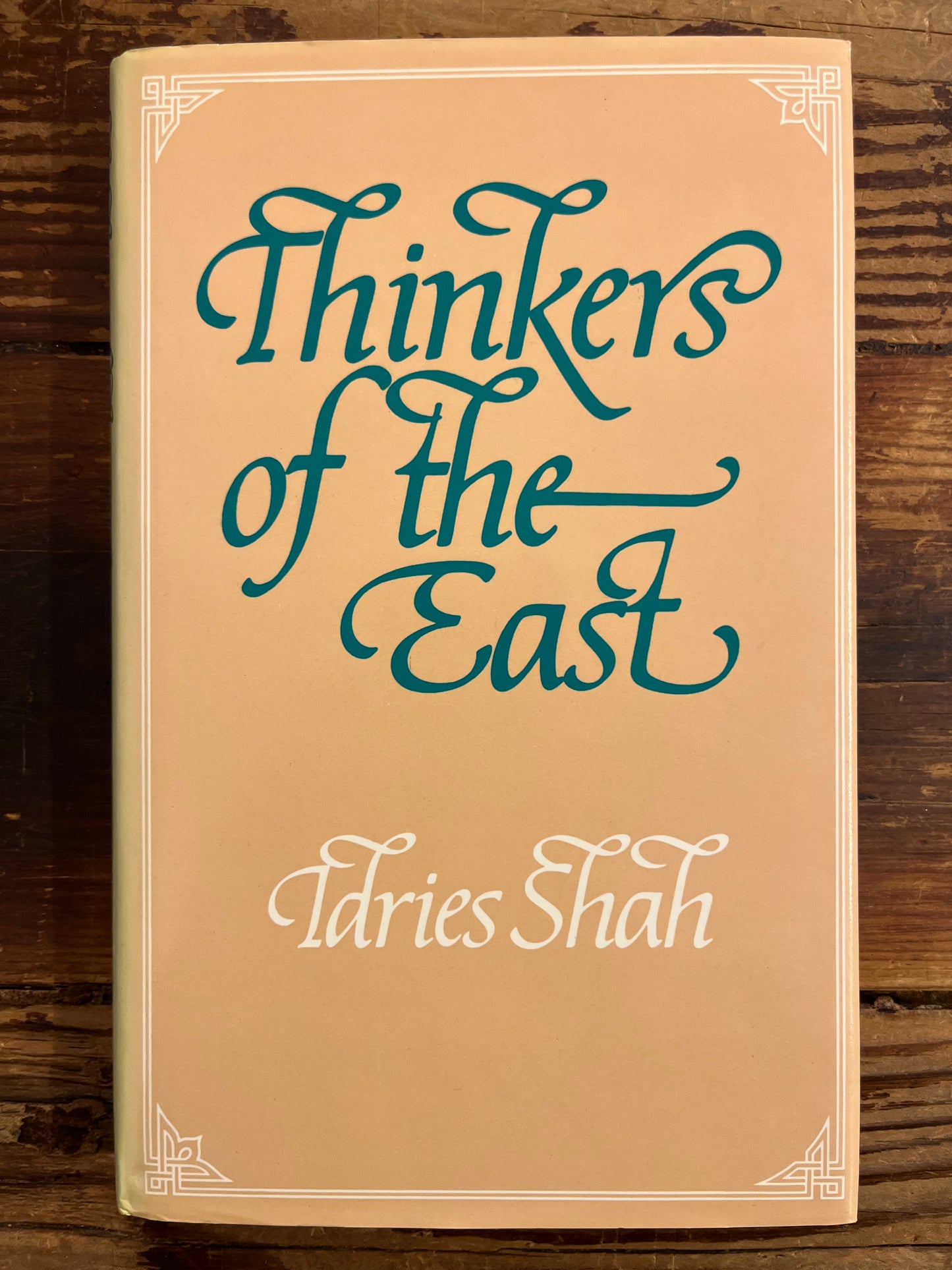 Book titled 'Thinkers of the East' by Idries Shah on a wooden surface