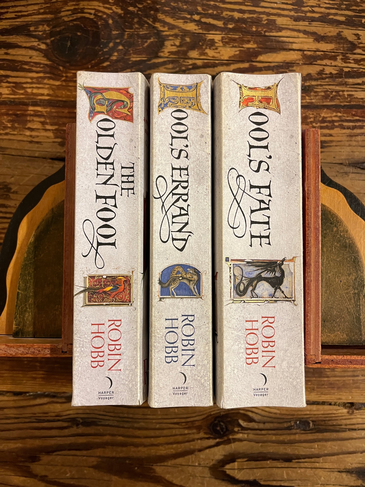 the spine of the three books of Robin Hobb's 'Tawny Man's trilogy' on a wooden surface