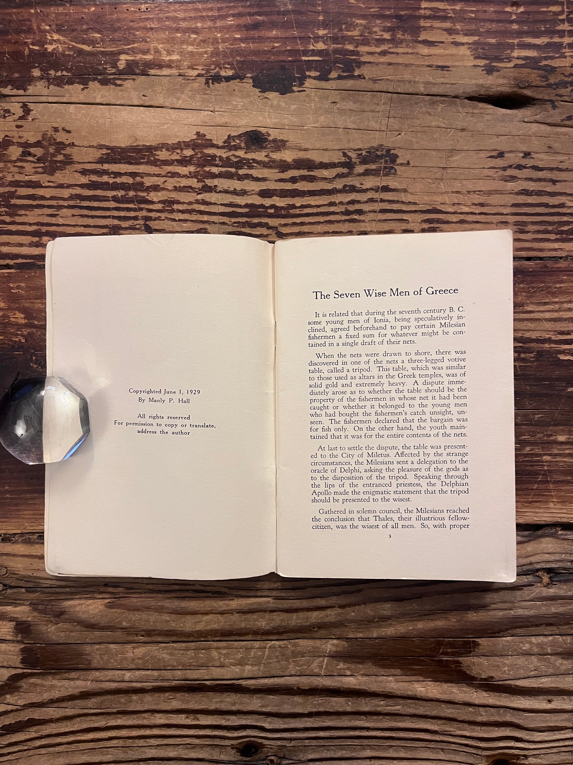 Open booklet titled 'KFI radio talks on philosophy and psychology' by Manly P. Hall on a wooden surface