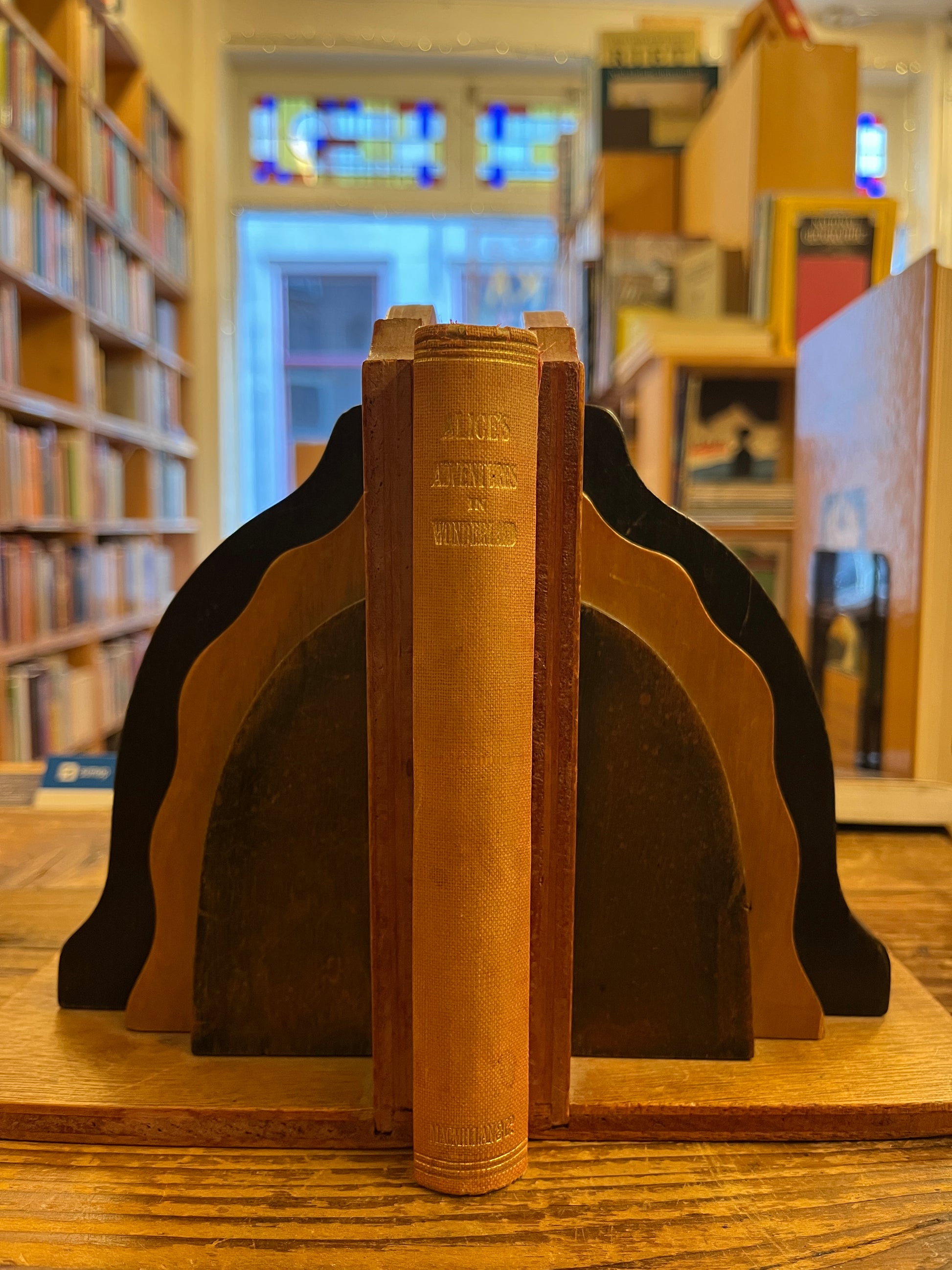 Spine of a 1922 macmillan & co miniature edition of 'Alice's adventures in wonderland' by Lewis Carroll on a wooden surface