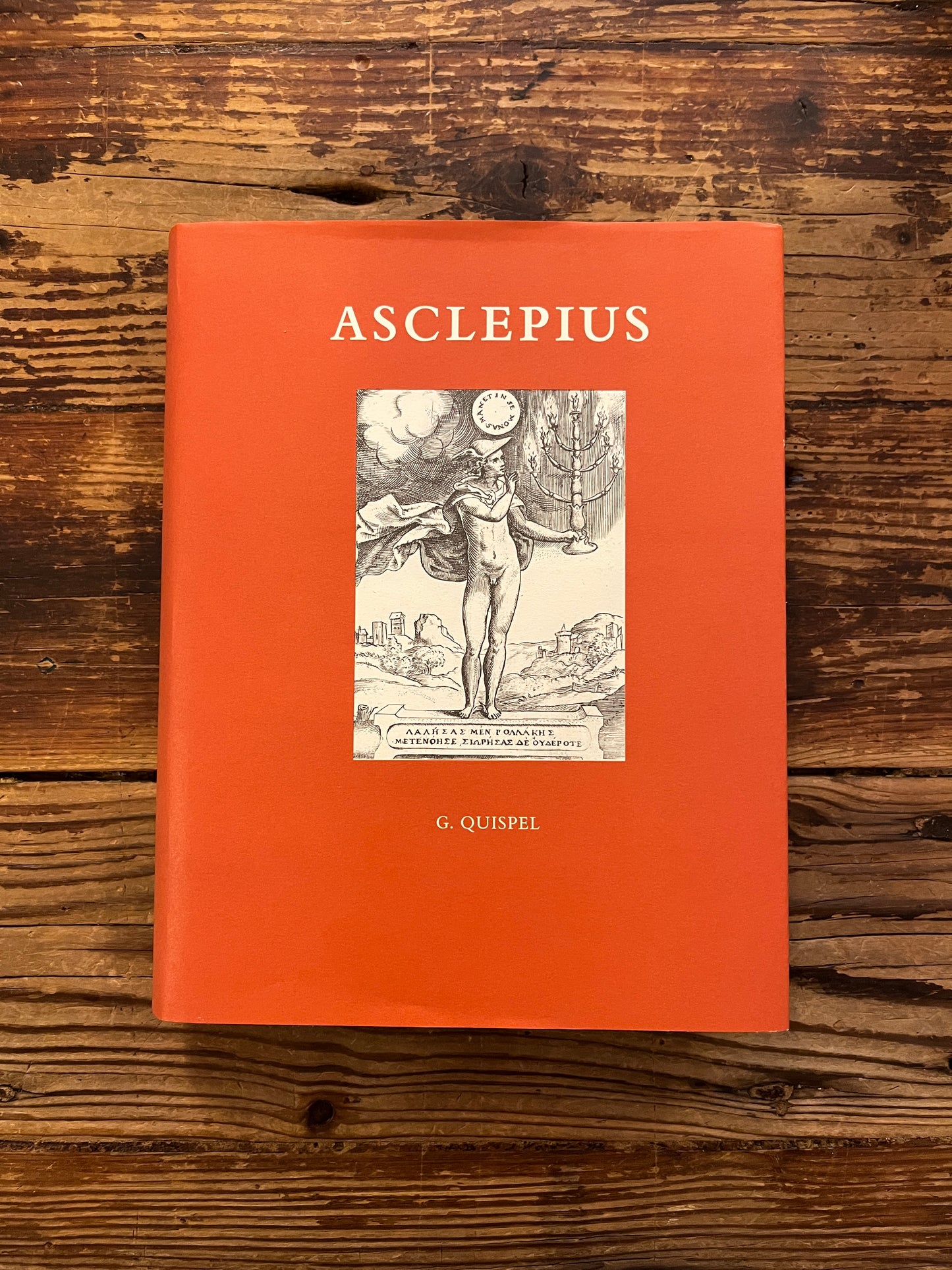 Voorkant van 'Asclepius' ingeleid, vertaald en toegelicht door G. Quispel op een houten achtergrond 