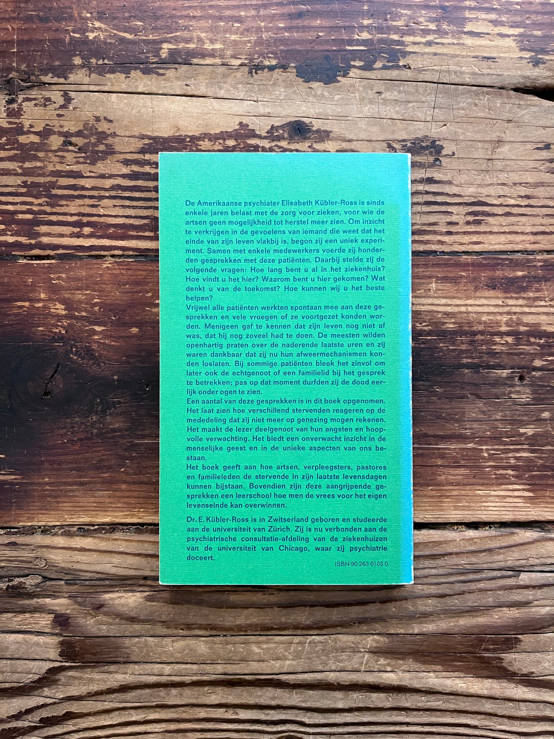 Achterkant van boek met de titel 'lessen voor levenden' door Elisabeth Kübler-Ross   op een houten achtergrond 