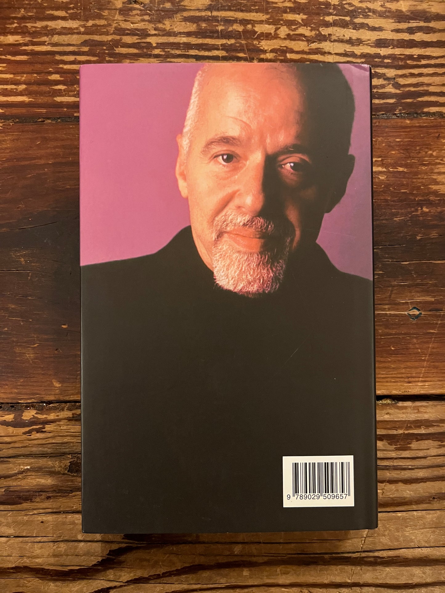 Achterkant van boek 'De Alchemist' door Paulo Coelho op houten achtergrond 