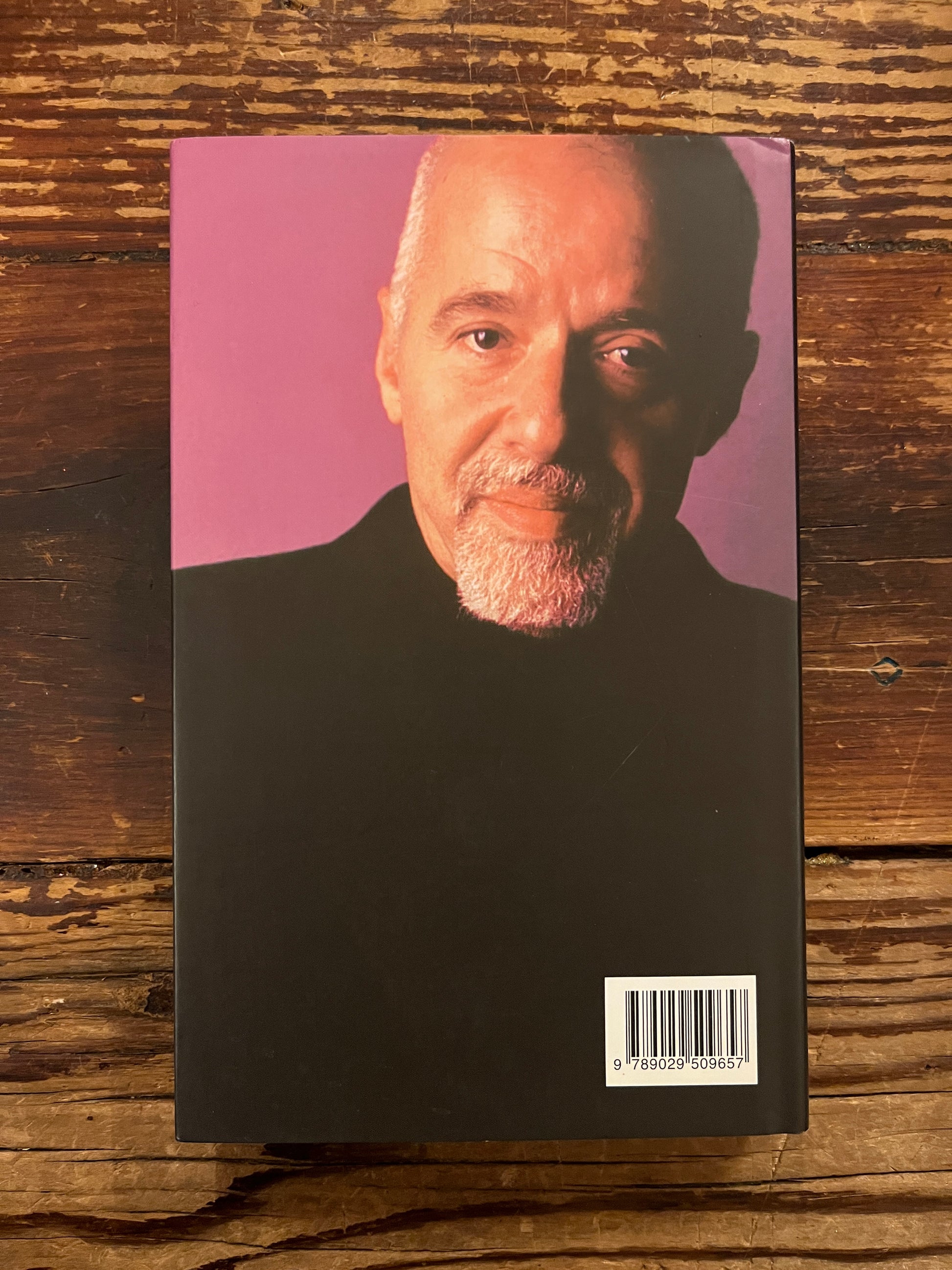 Achterkant van boek 'De Alchemist' door Paulo Coelho op houten achtergrond 
