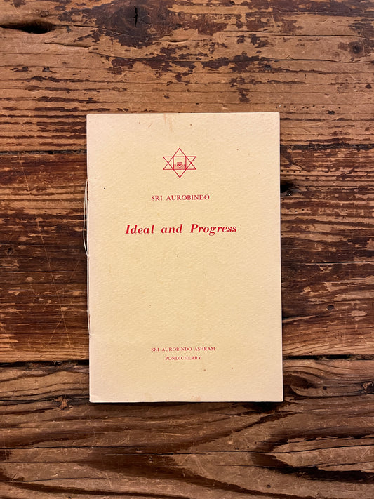Book titled 'Ideal and Progress' by Sri Aurobindo on a wooden surface