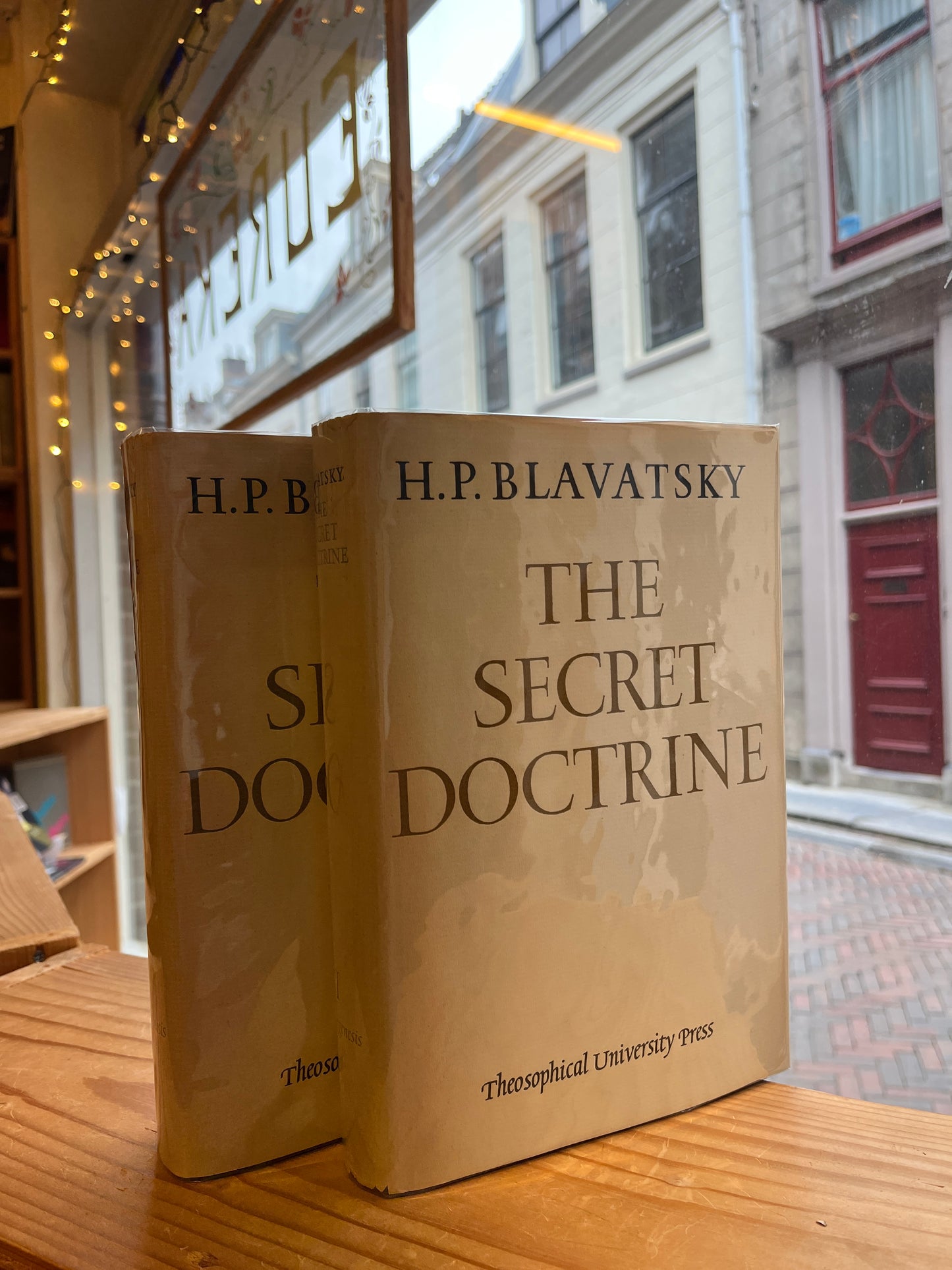 Two books titled 'The Secret Doctrine' by H.P. Blavatsky on a wooden surface.