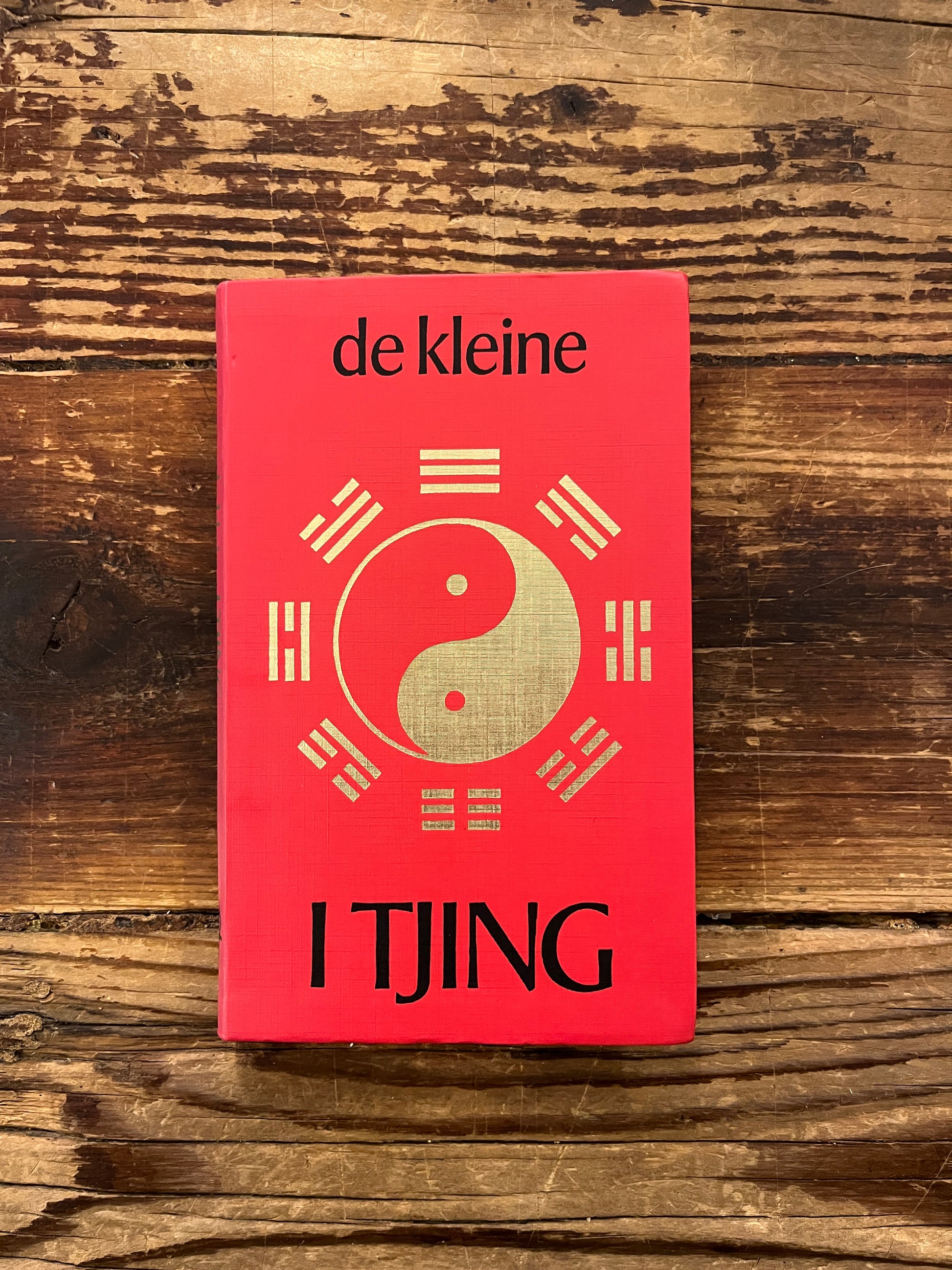 Boek met de titel 'de kleine I Tjing' op een houten achtergrond 