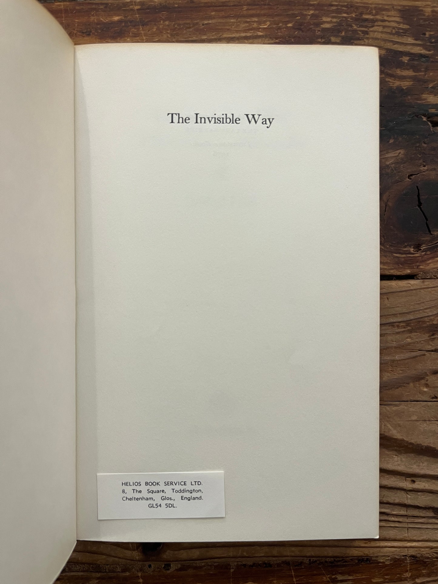 Open book with the title 'the invisible way' by Reshad Feild on a wooden surface 