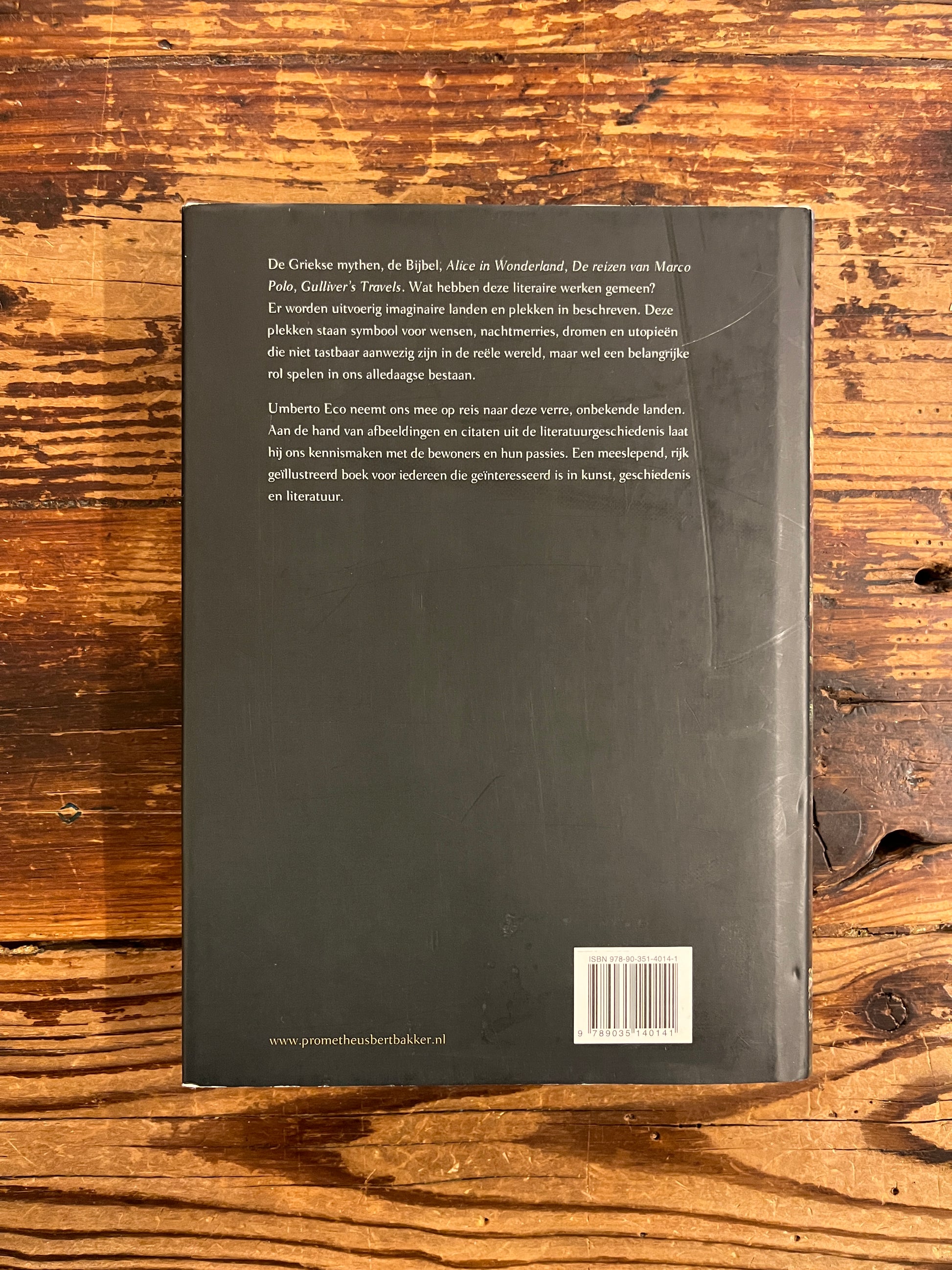 Achterkant van boek met de titel 'De Geschiedenis Van Imaginaire Landen En Plaatsen' door Umberto Eco op een houten achtergrond 