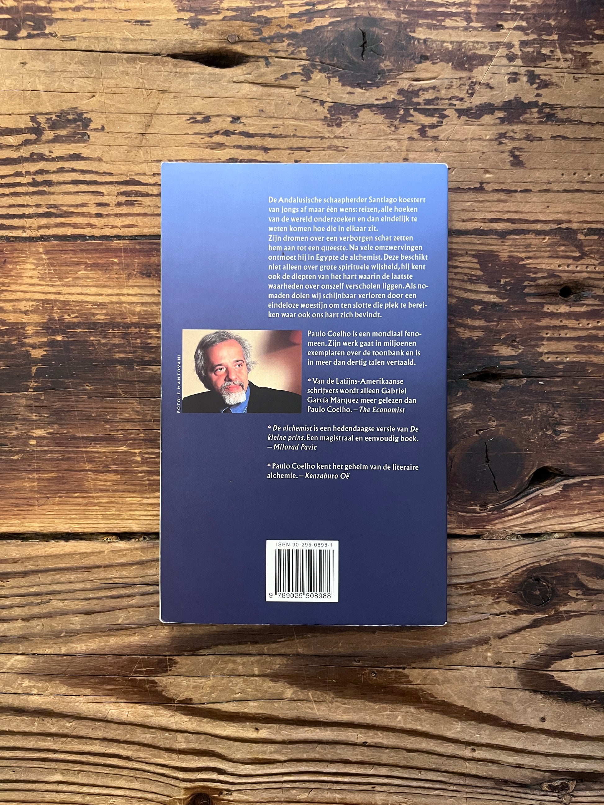 Achterkant van boek met de titel 'de alchemist' door Paulo Coelho op een houten achtergrond 