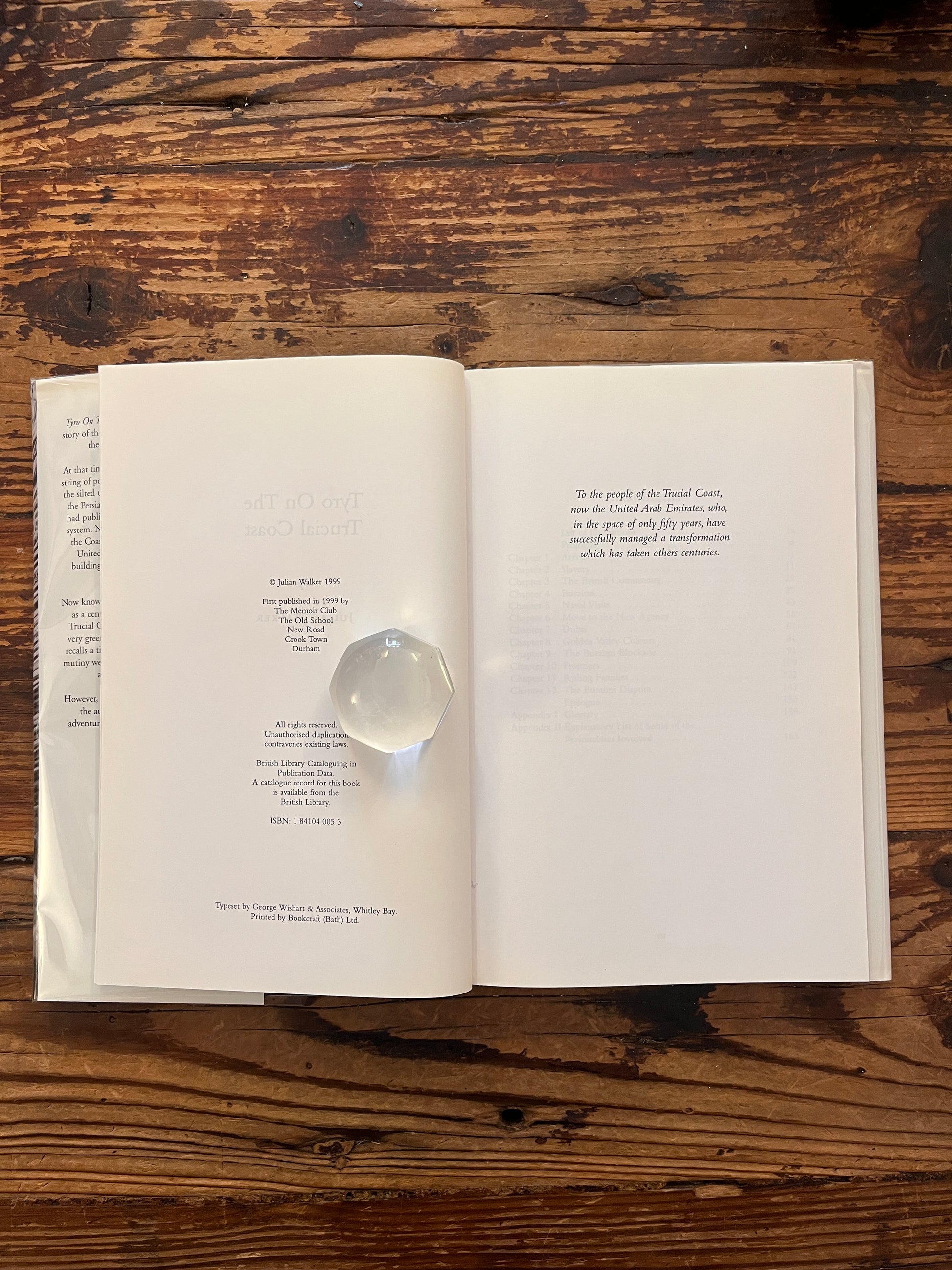 Publisher page of book with the title 'Tyro on the Trucial Coast' by Julian Walker on a wooden surface