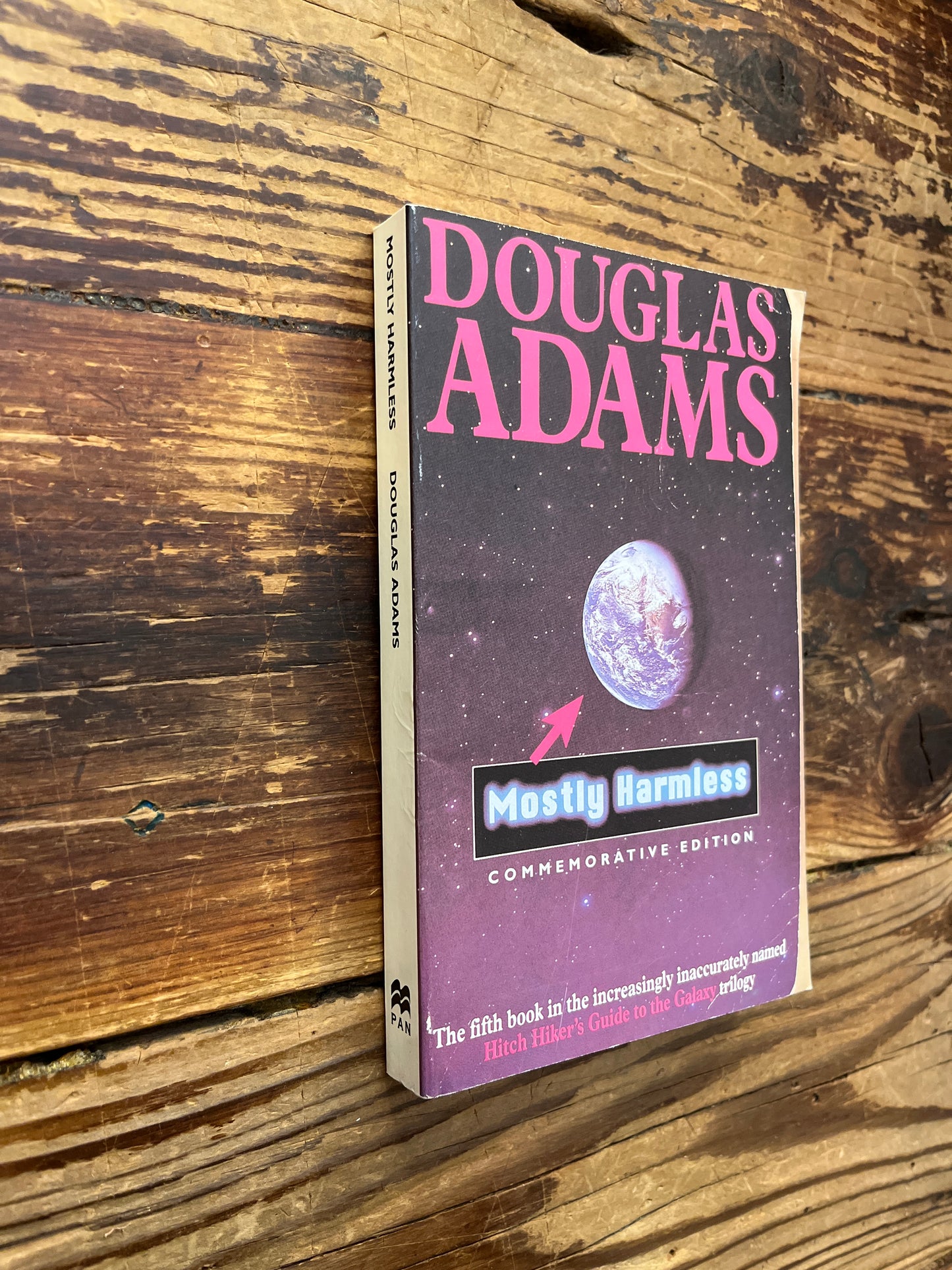 Book titled 'Mostly Harmless' by Douglas Adams on a wooden surface
