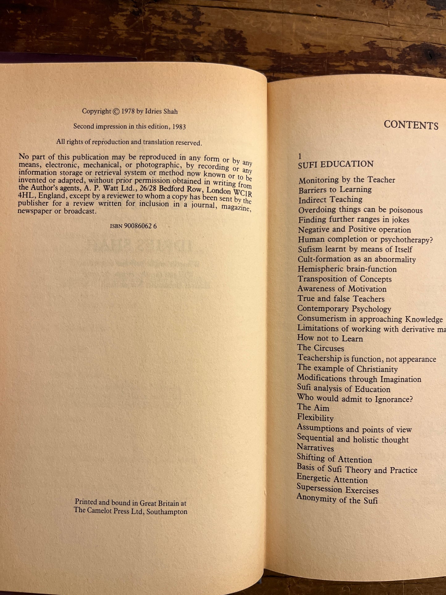 Open book titled 'A Perfumed Scorpion' by Idries Shah with text on a wooden surface