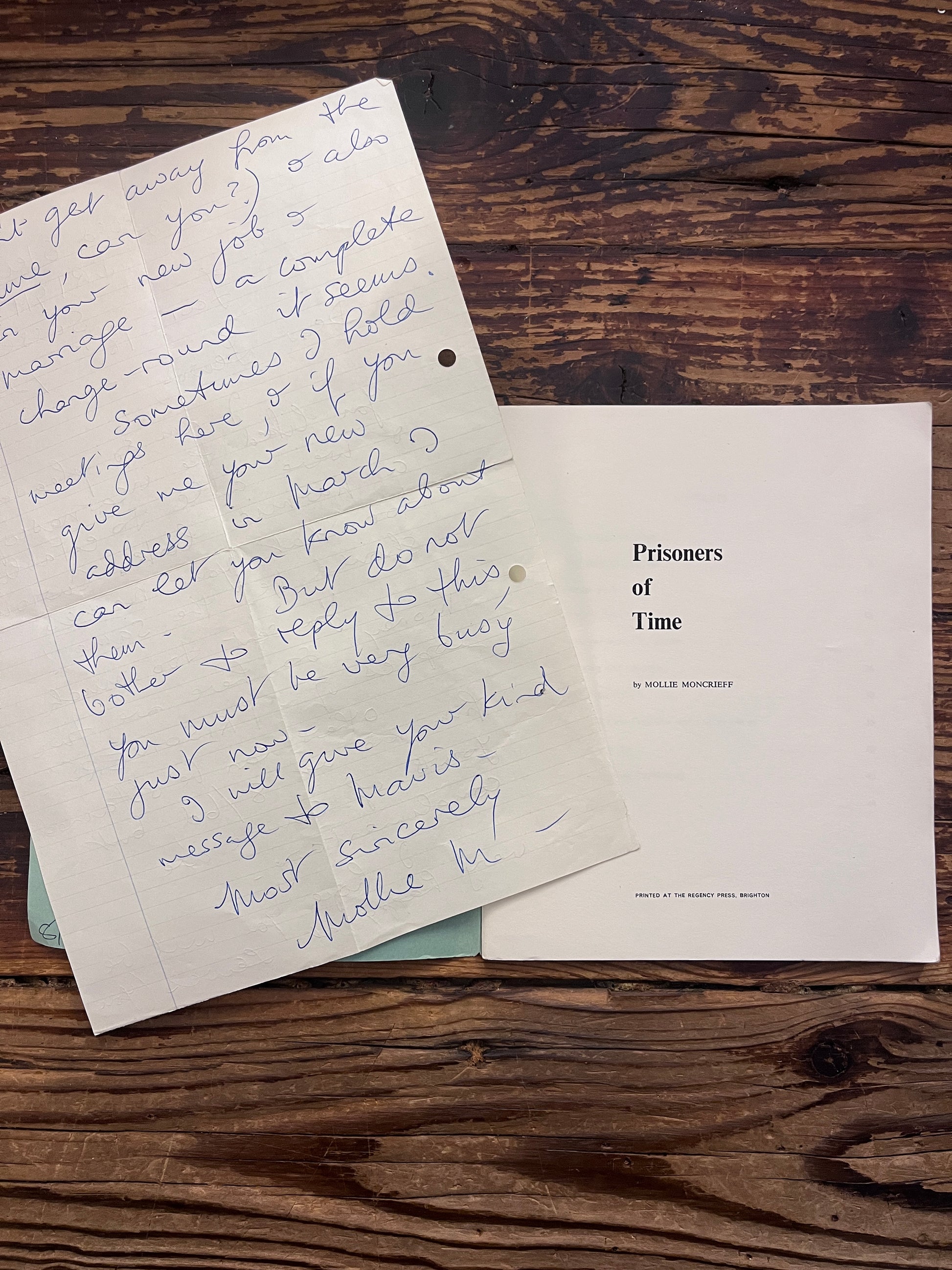 Written and signed letter by Mollie Moncrieff in an open booklet with the title 'Prisoners of time' by Mollie Moncrieff on a wooden surface 