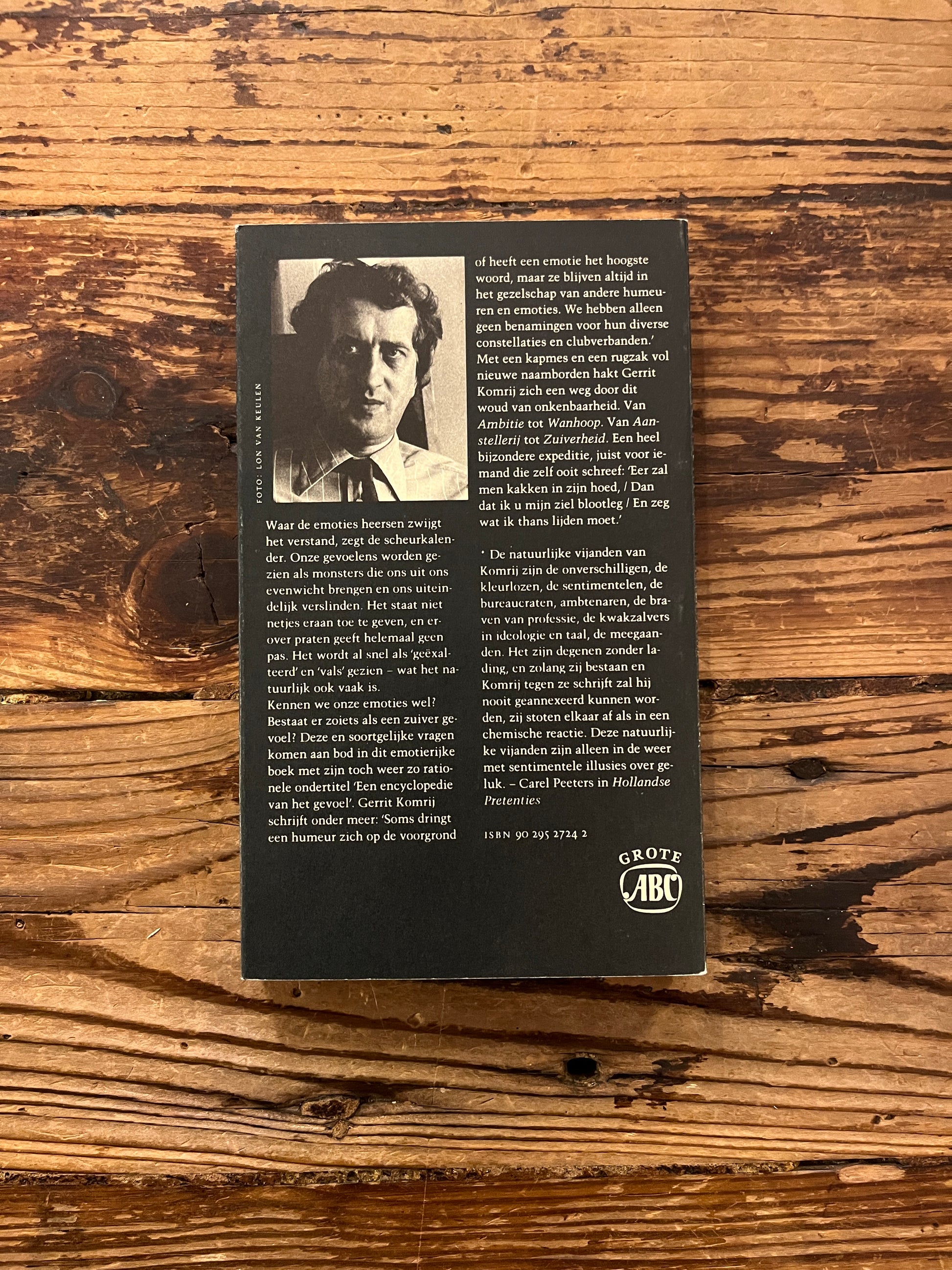 Achterkant boek met de titel 'humeuren & temperamenten' door Gerrit Komrij op een houten achtergrond 