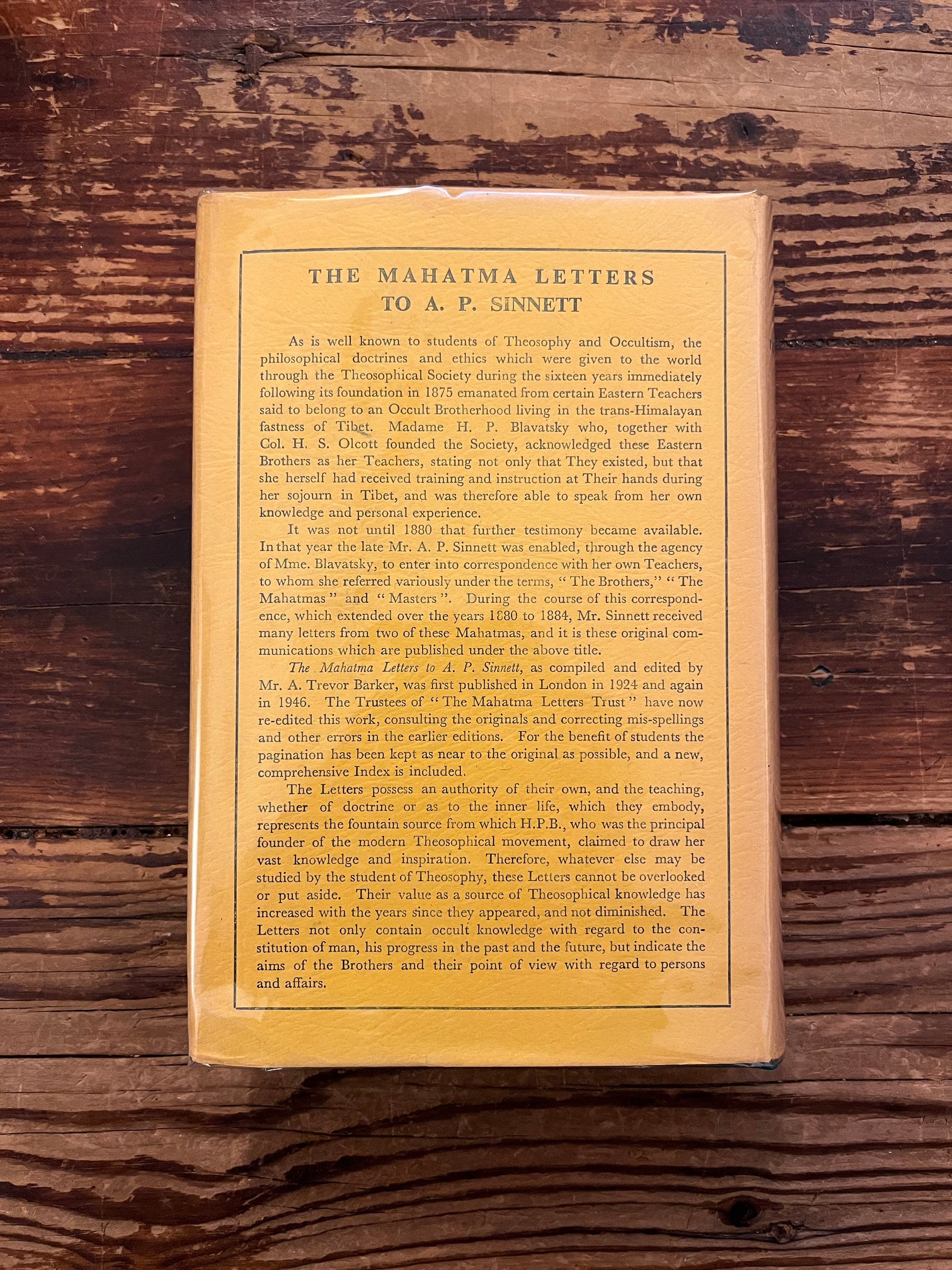 Back cover of book titled 'the Mahatma letter to A.P. Sinnett' on a wooden surface 
