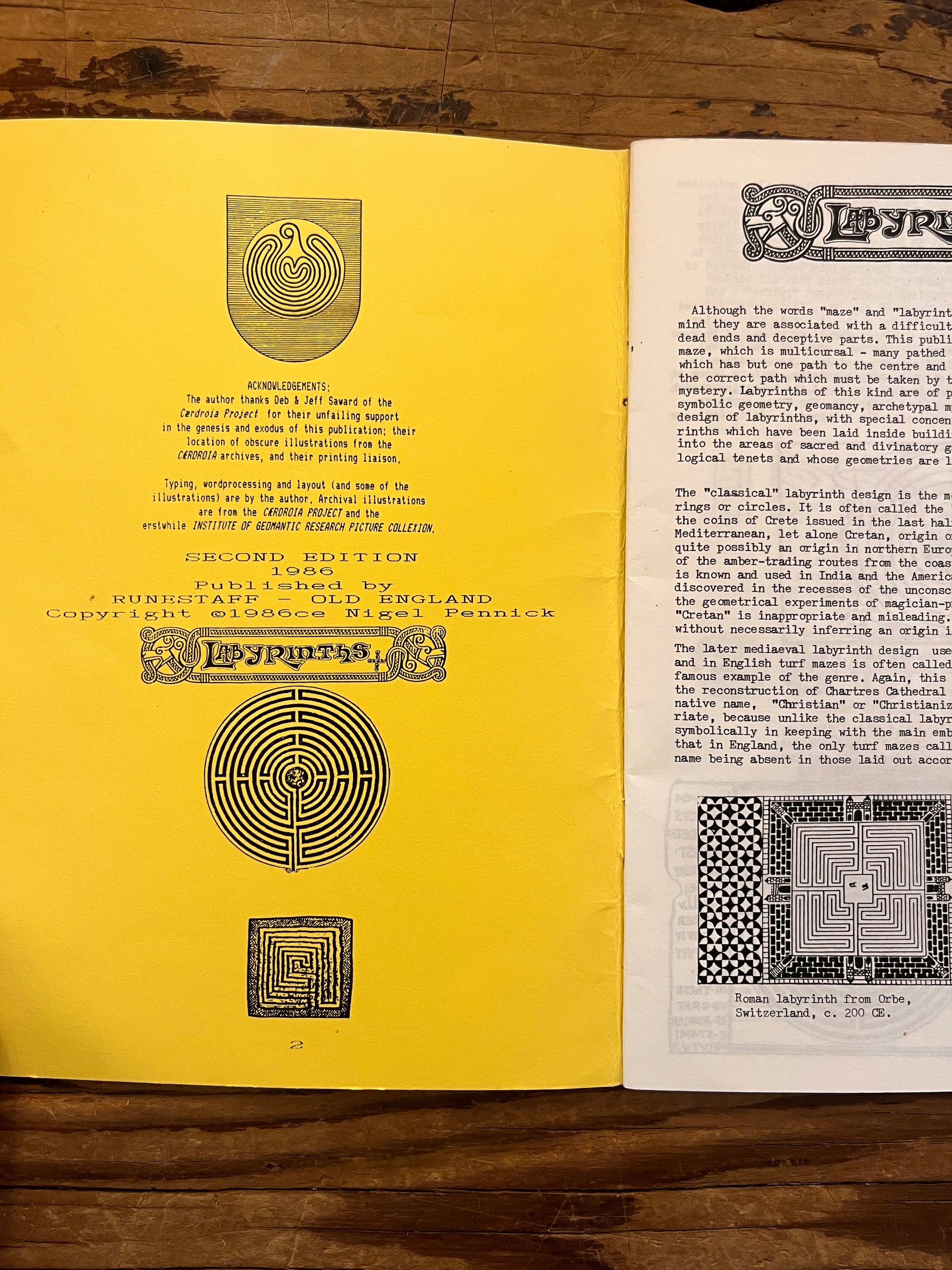 Open booklet with the title 'Labyrinths, their geomancy and symbolism' by Nigel Pennick on a wooden surface 
