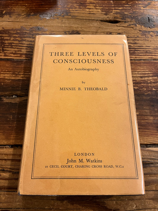 Cover of book 'three levels of consciousness' by Minnie B. Theobald on a wooden surface 