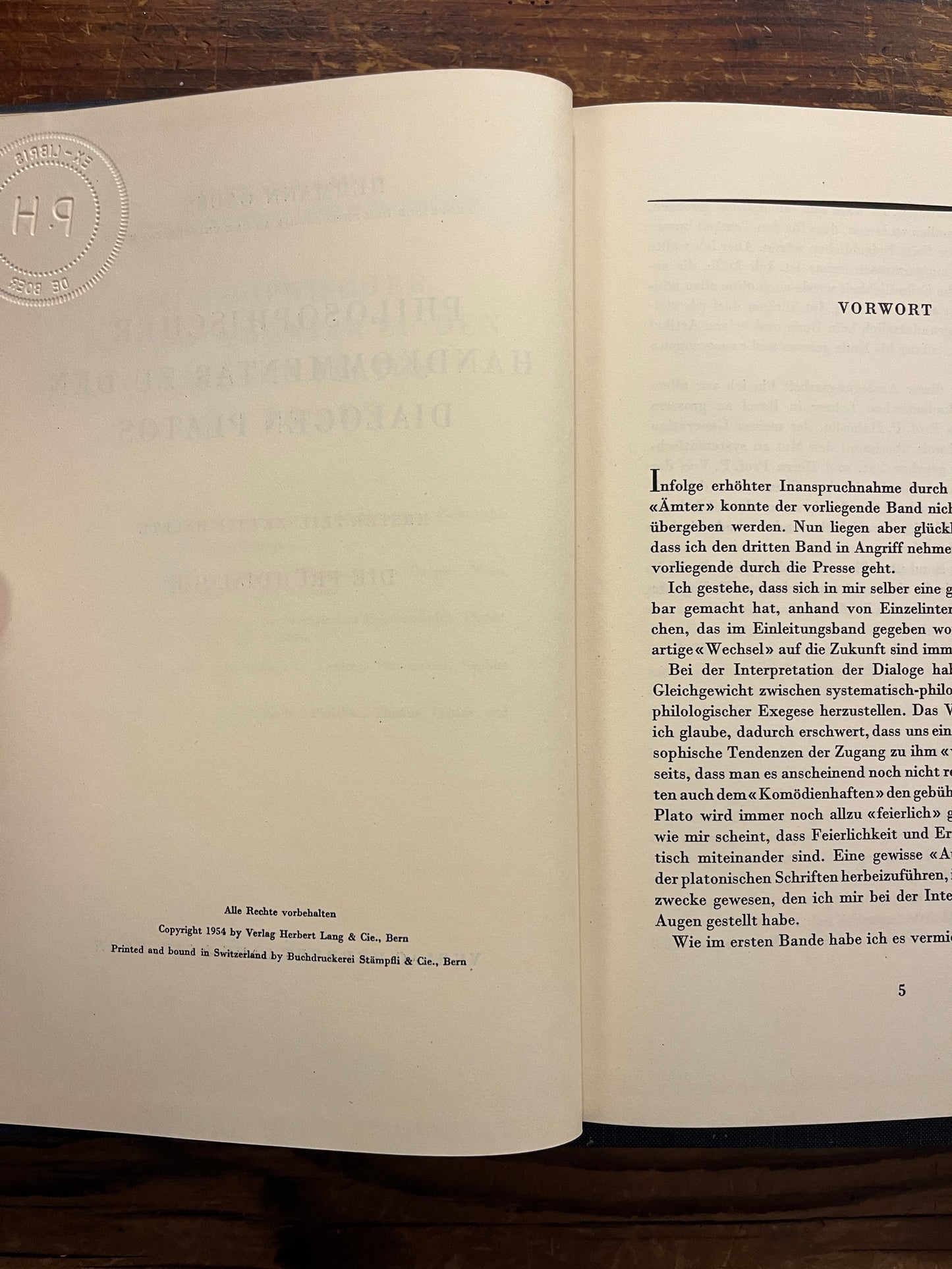 Open book titled 'Philosophischer Handkommentar zu den Dialogen Platos' by H. Gauss on a wooden surface 