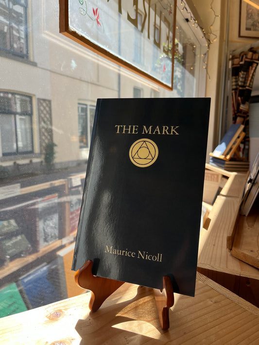 Book titled 'The Mark' by Maurice Nicoll held in front of a window with reflections.