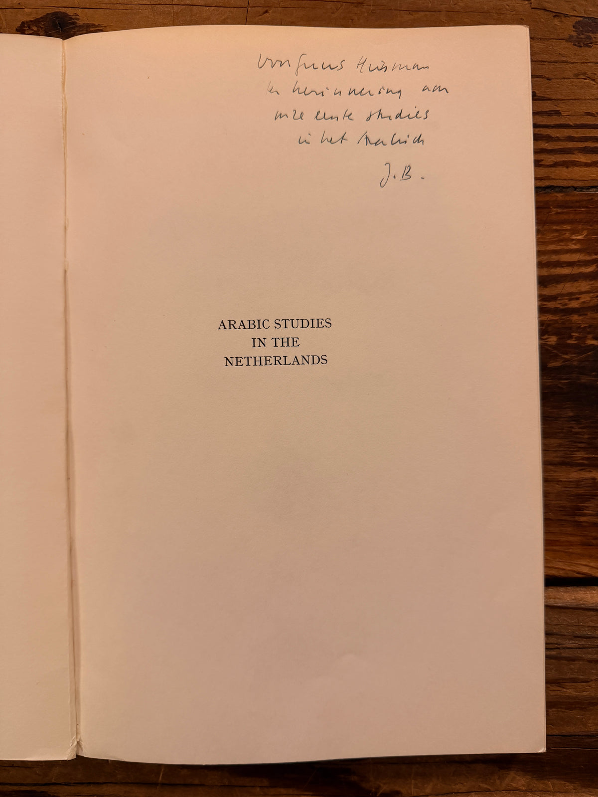 Note from the author on the first page of a book titled 'Arabic Studies in the Netherlands' by J. Brugman en F. Schröder, lying on a wooden surface