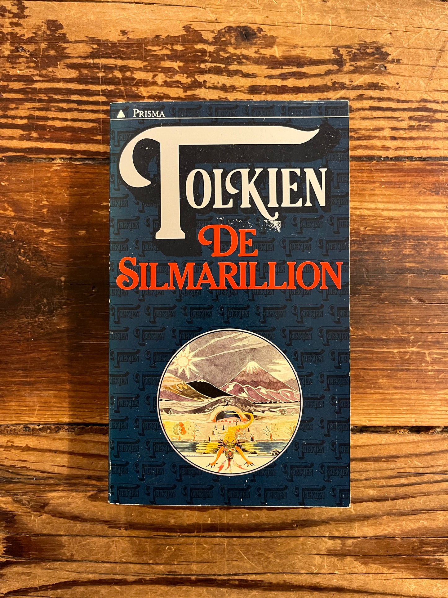 Voorkant van boek met de titel 'De Silmarillion' by J.R.R. Tolkien op een houten achtergrond 